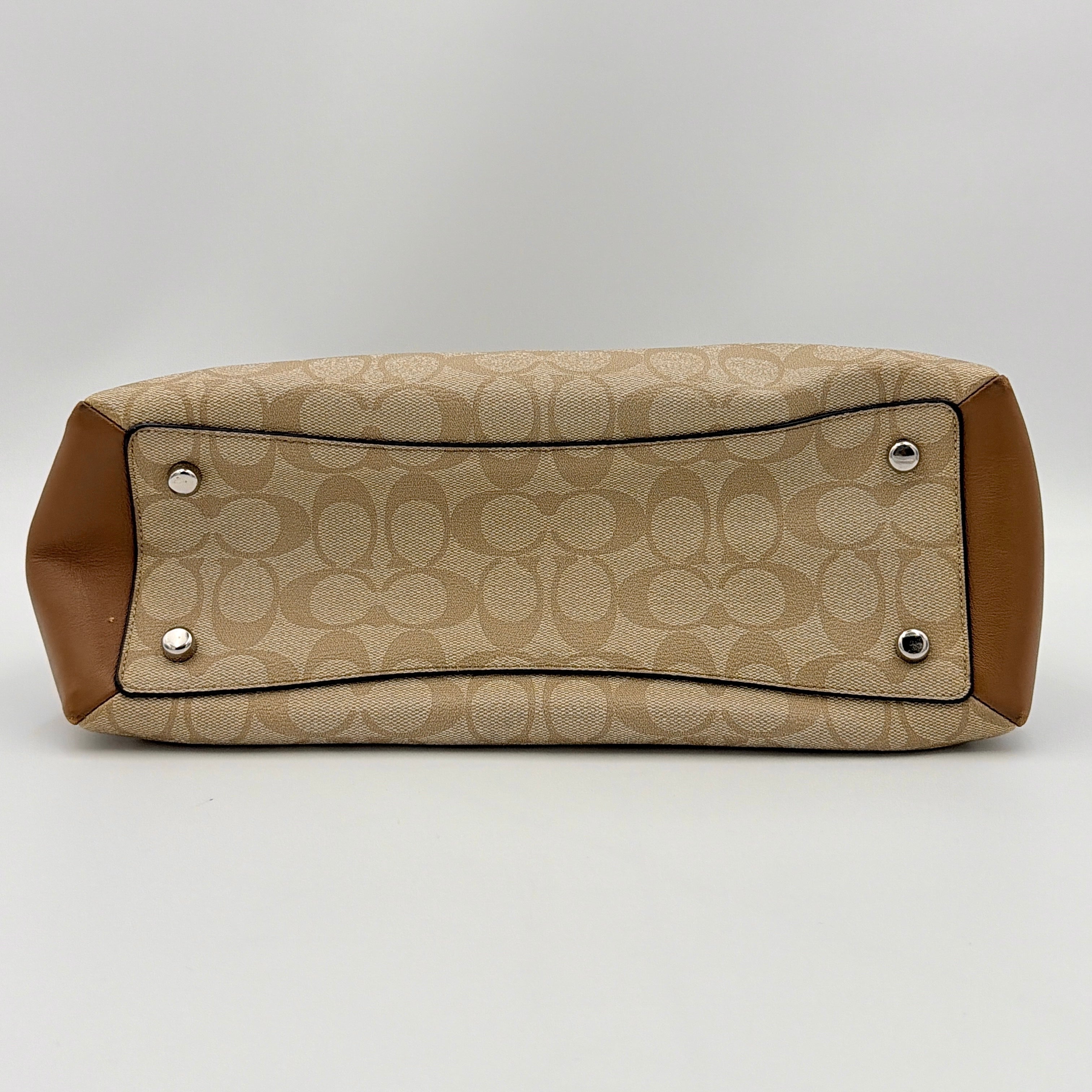 Coach Signature Sage Carryall in beige monogram canvas and tan leather with black handles, styled as an elegant, softly structured handbag.
