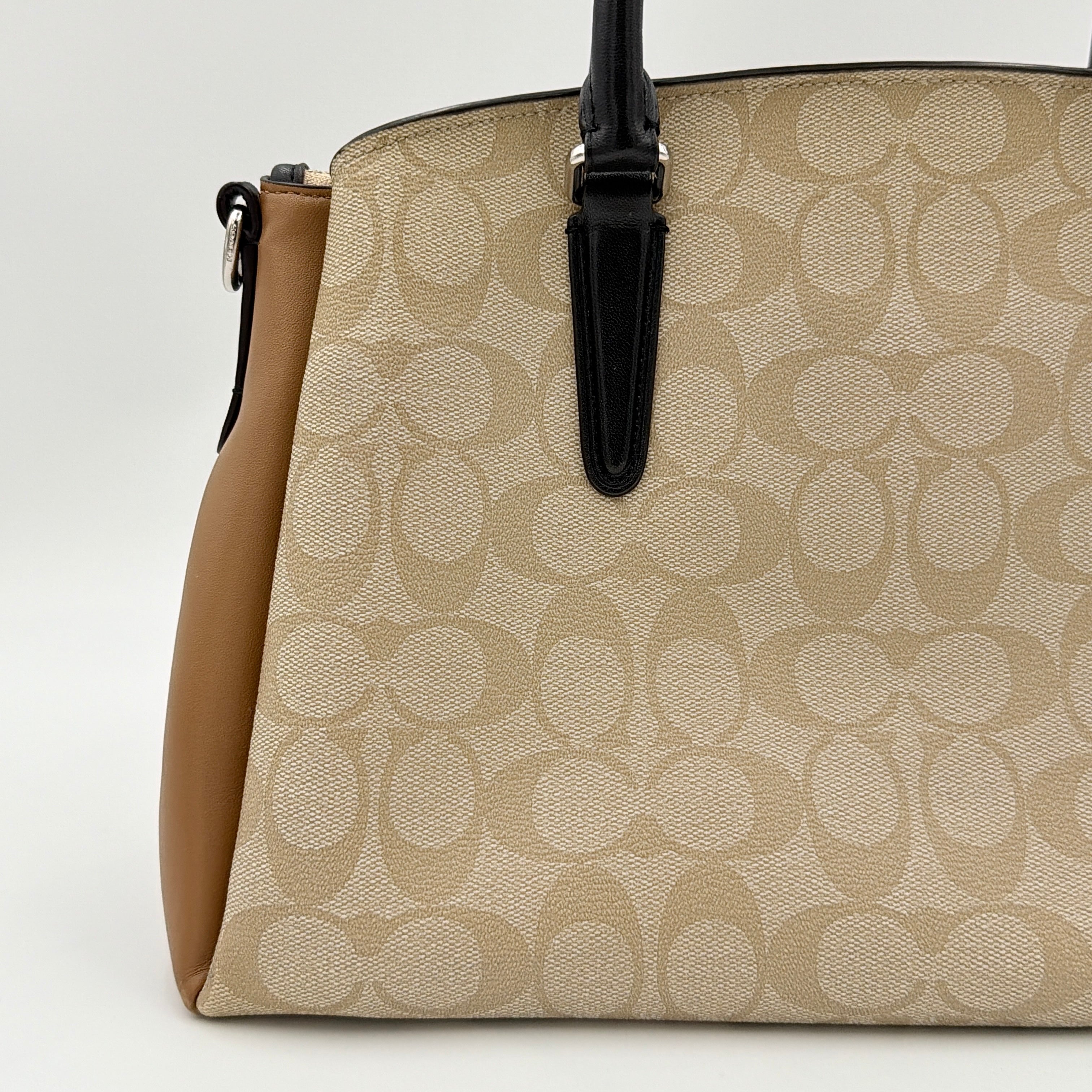 Coach Signature Sage Carryall in beige monogram canvas and tan leather with black handles, styled as an elegant, softly structured handbag.