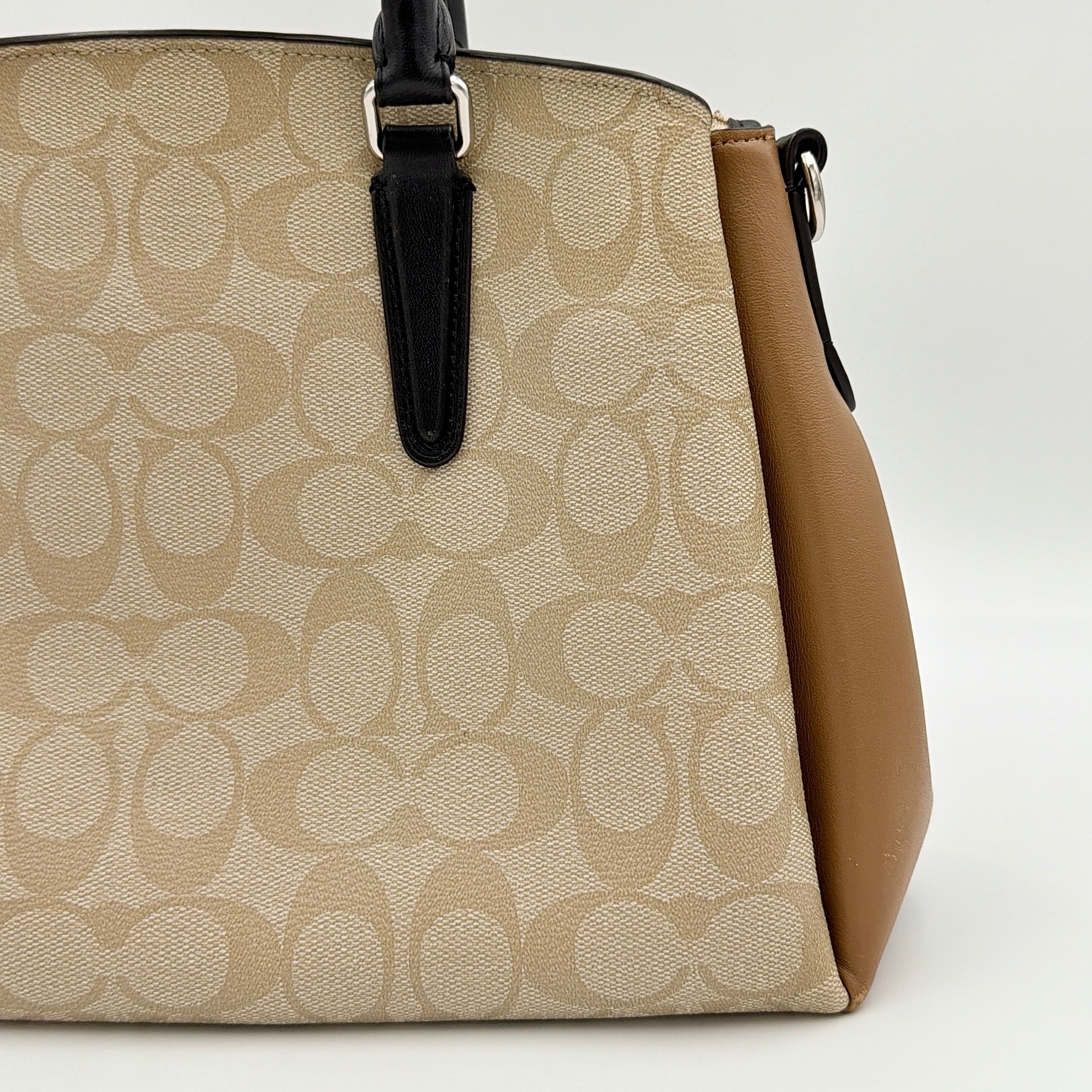 Coach Signature Sage Carryall in beige monogram canvas and tan leather with black handles, styled as an elegant, softly structured handbag.