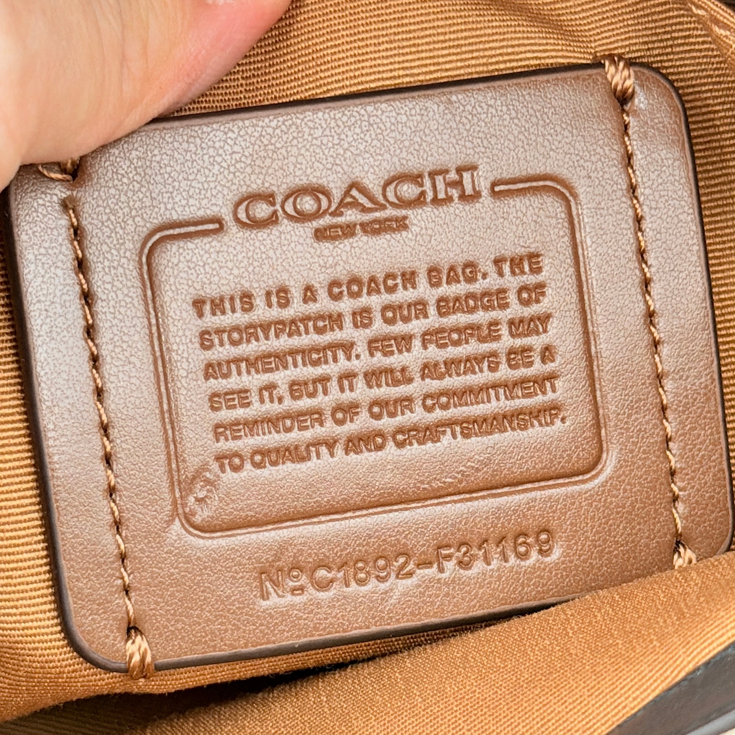 Coach Signature Sage Carryall in beige monogram canvas and tan leather with black handles, styled as an elegant, softly structured handbag.