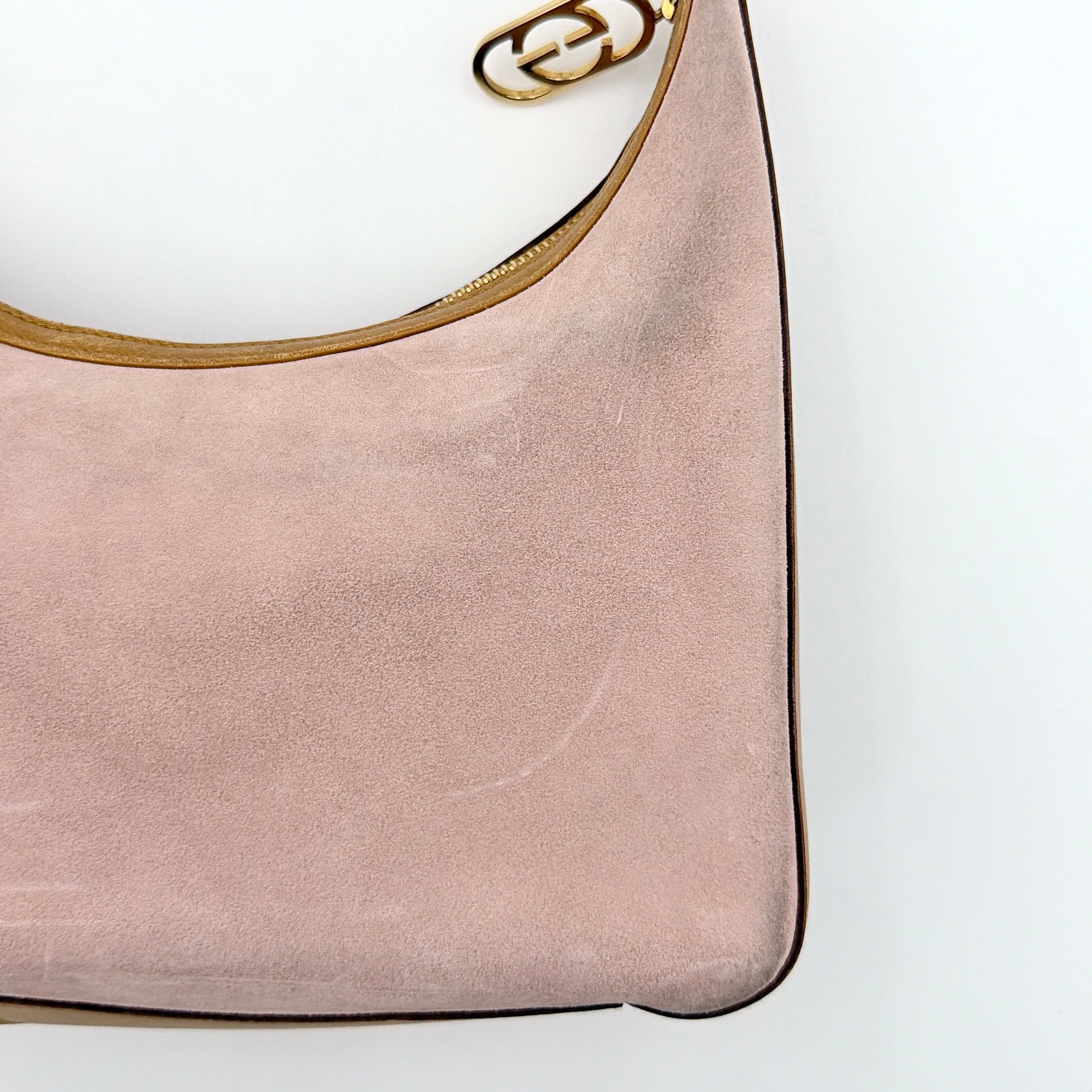 Gucci hobo shoulder bag in blush pink suede with tan leather trim and gold hardware, displayed against a white background.