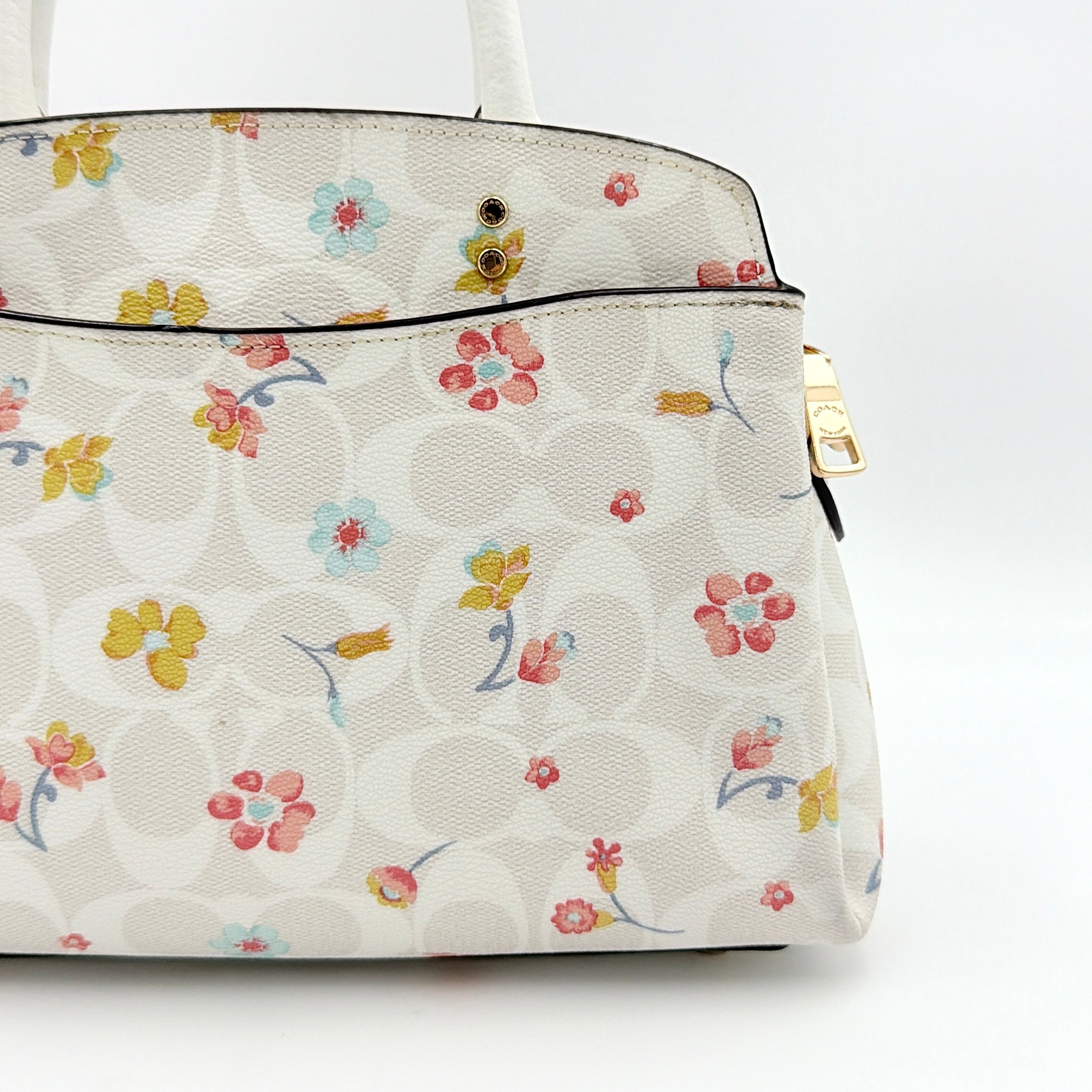 Coach 2Way Signature Lillie Carryall in white canvas with gold hardware and multicolour floral print, accompanied by a detachable white shoulder strap.