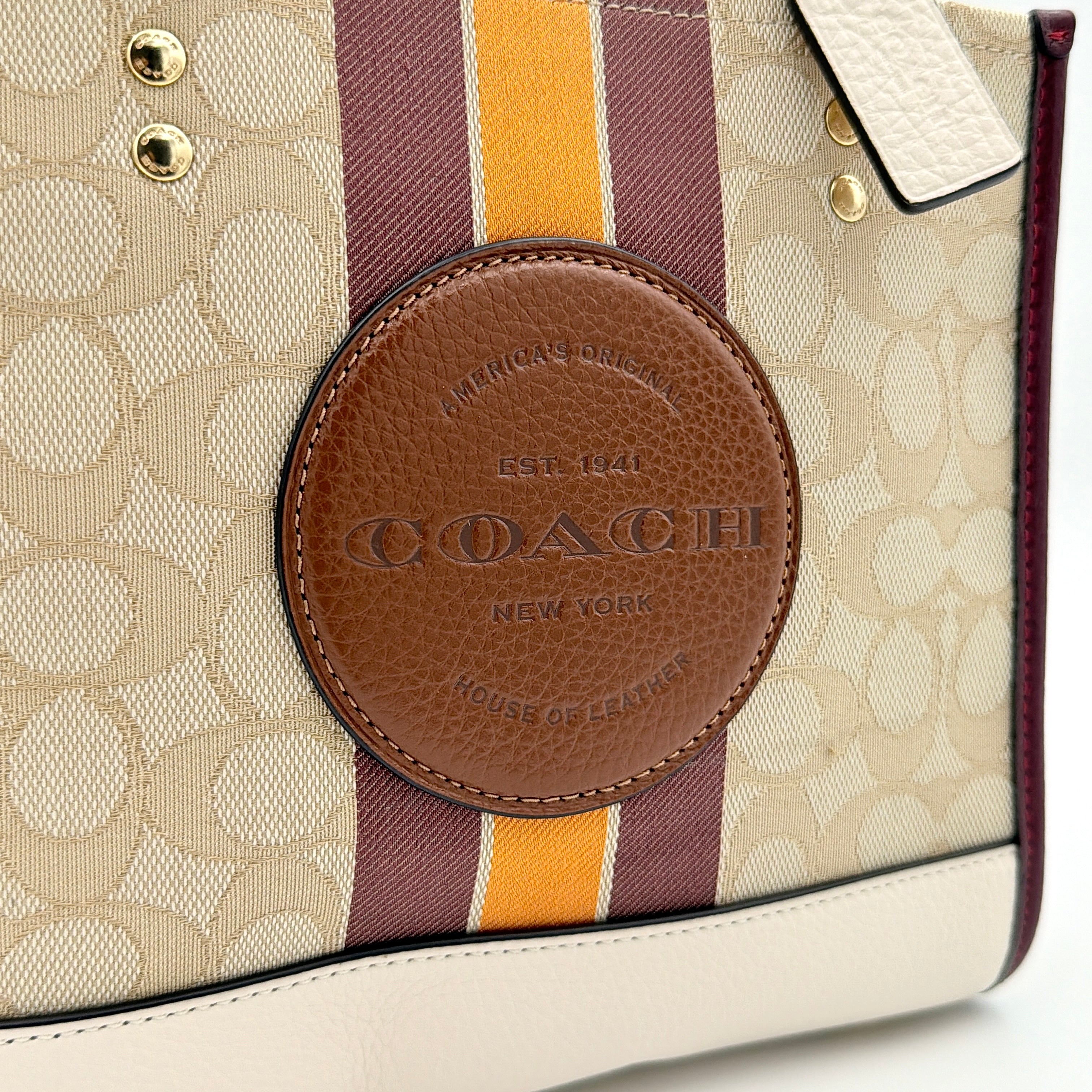 Coach Signature Dempsey 22 Stripe Tote Bag in beige canvas with bold vertical stripes, leather trims, logo patch, and detachable strap.