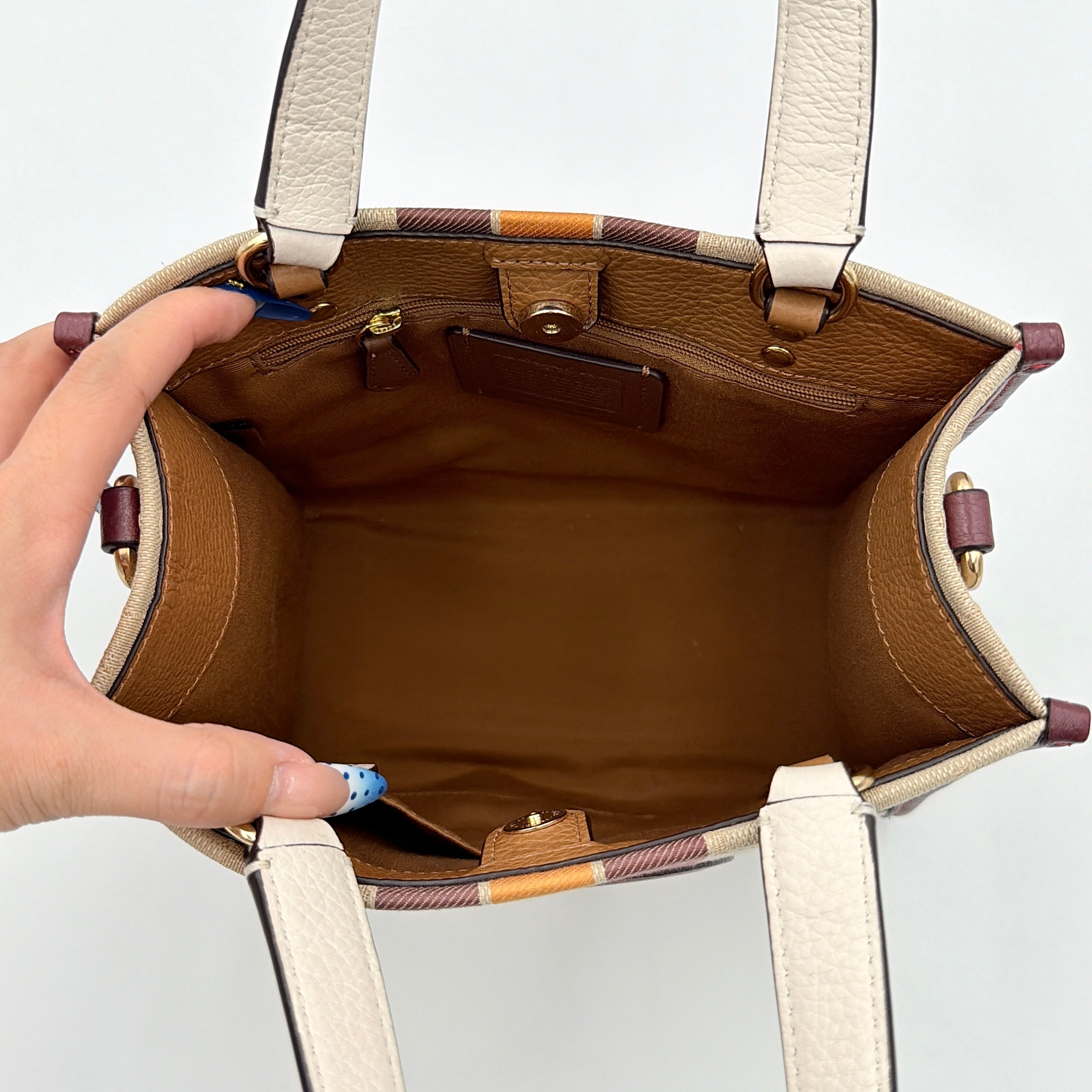 Coach Signature Dempsey 22 Stripe Tote Bag in beige canvas with bold vertical stripes, leather trims, logo patch, and detachable strap.