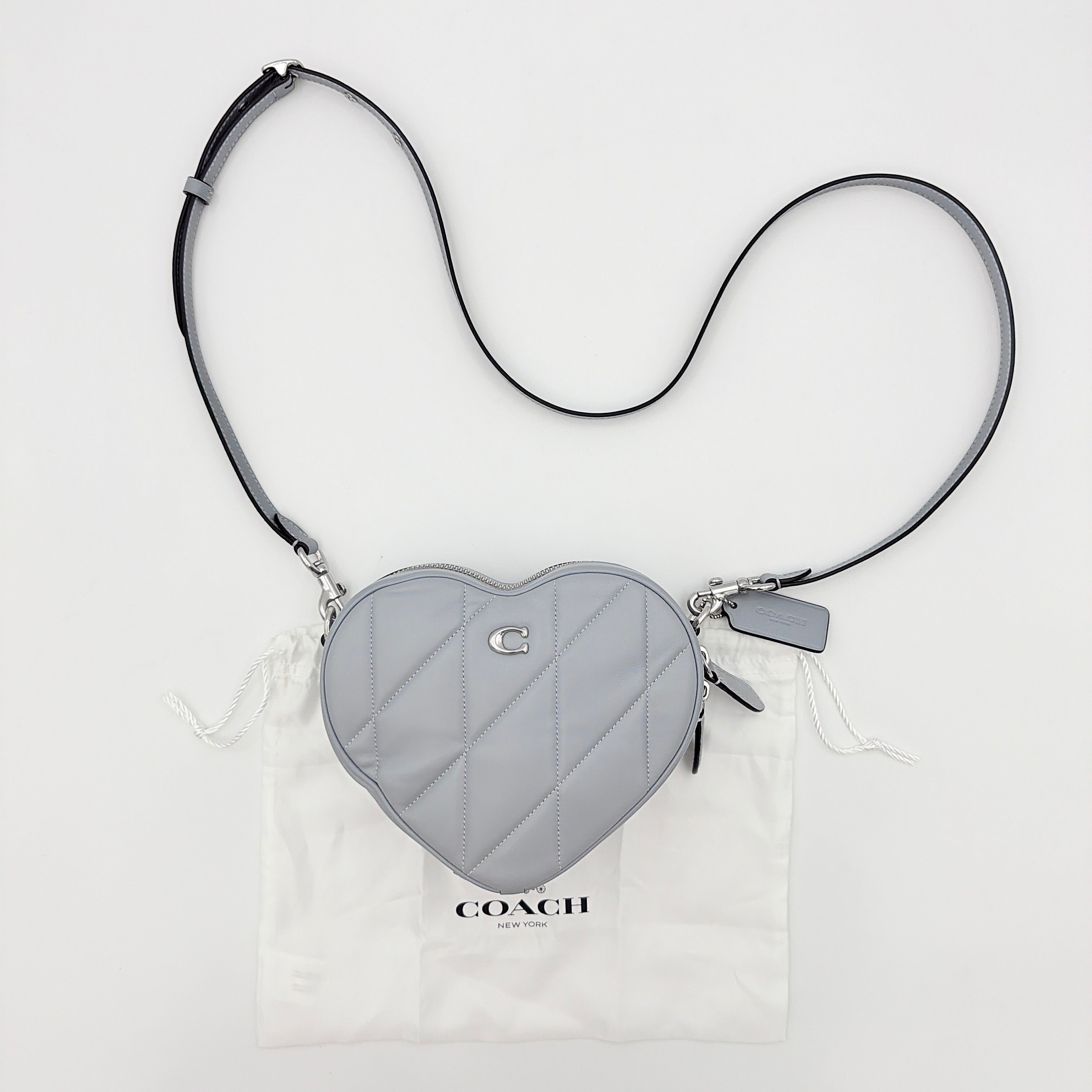 Coach heart-shaped quilted grey crossbody bag with silver hardware and adjustable strap.