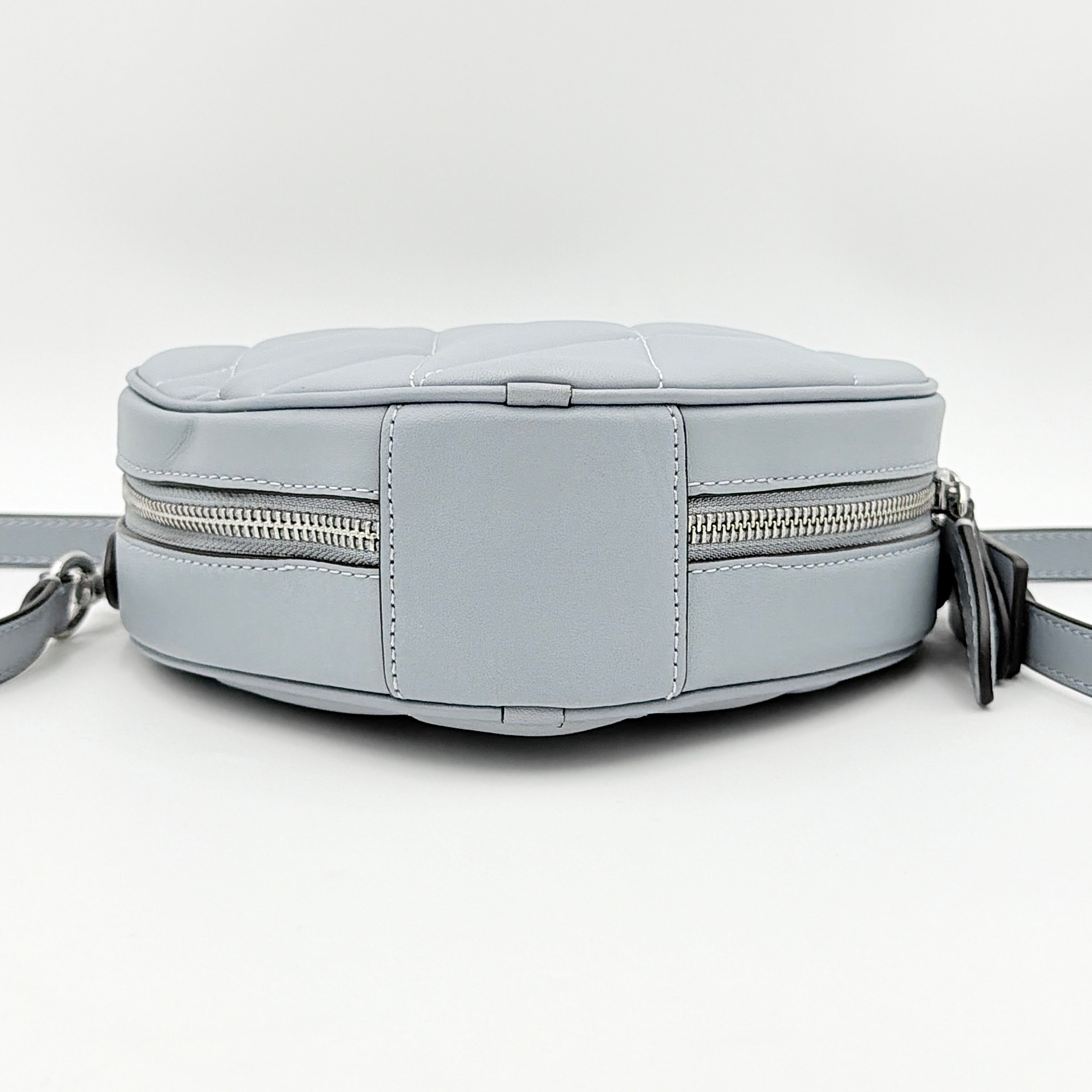 Coach heart-shaped quilted grey crossbody bag with silver hardware and adjustable strap.