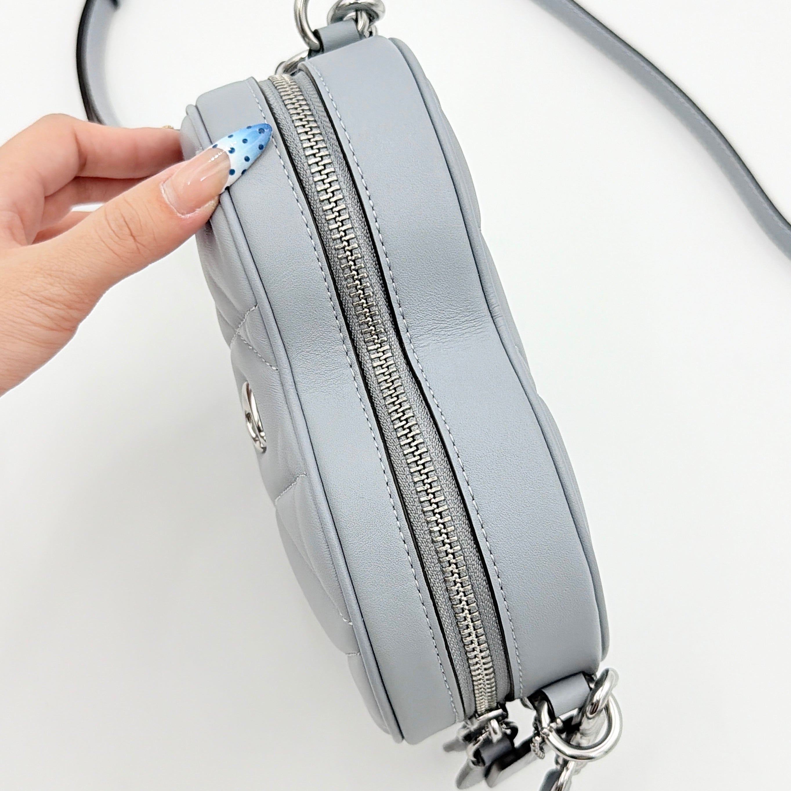Coach heart-shaped quilted grey crossbody bag with silver hardware and adjustable strap.