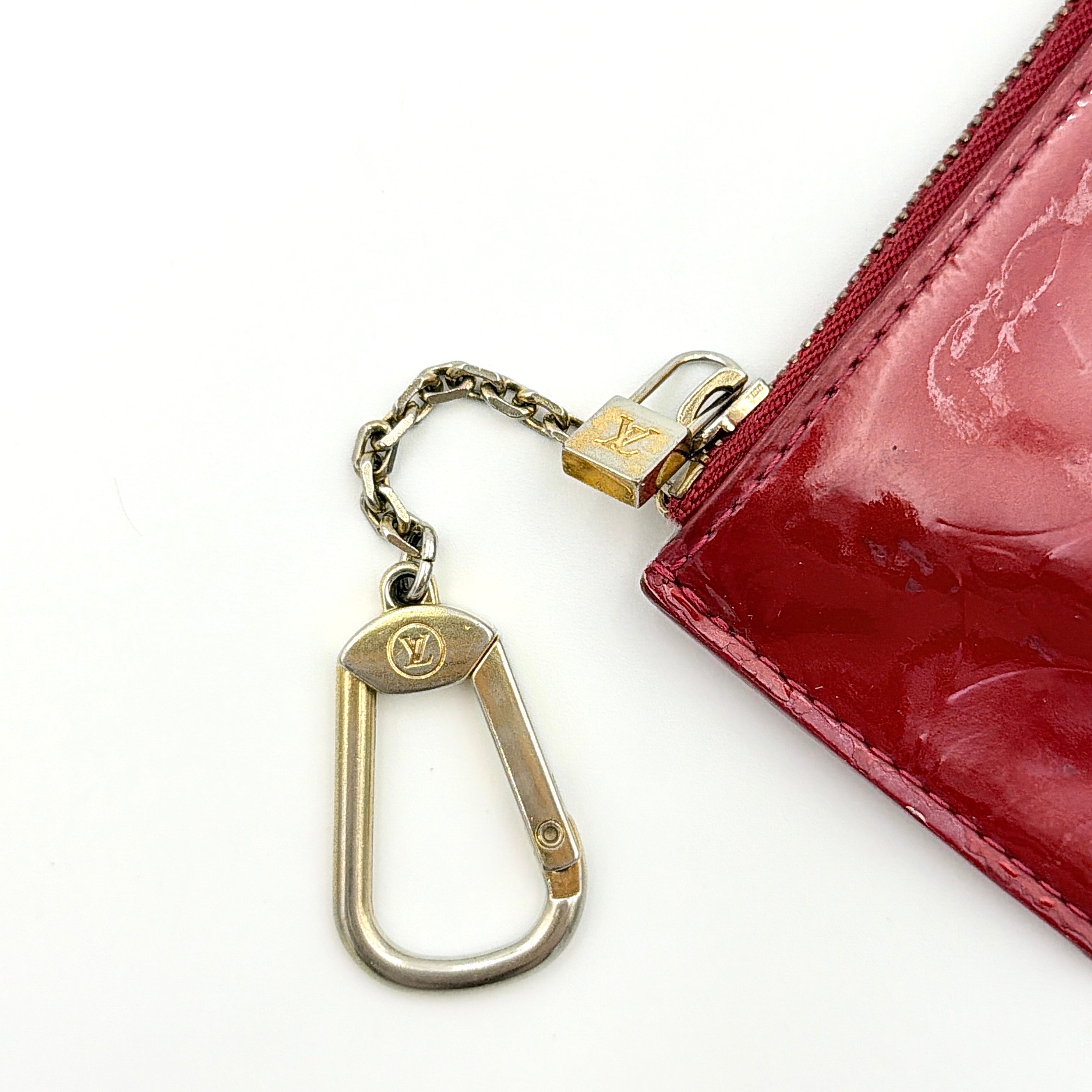 Louis Vuitton Vernis Coin Case in amethyst red patent leather with gold-tone key chain and zip closure, embossed with monogram pattern.
