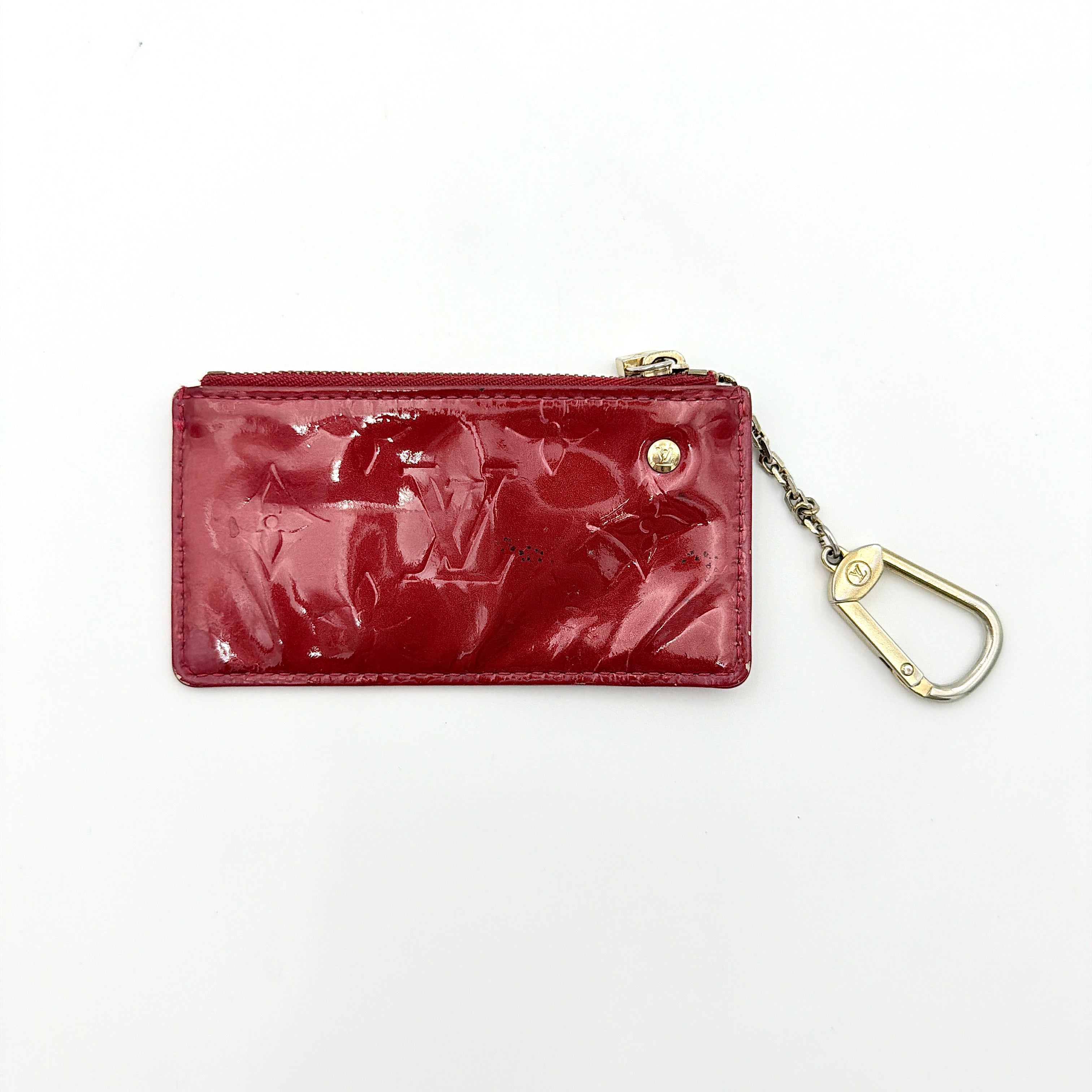 Louis Vuitton Vernis Coin Case in amethyst red patent leather with gold-tone key chain and zip closure, embossed with monogram pattern.