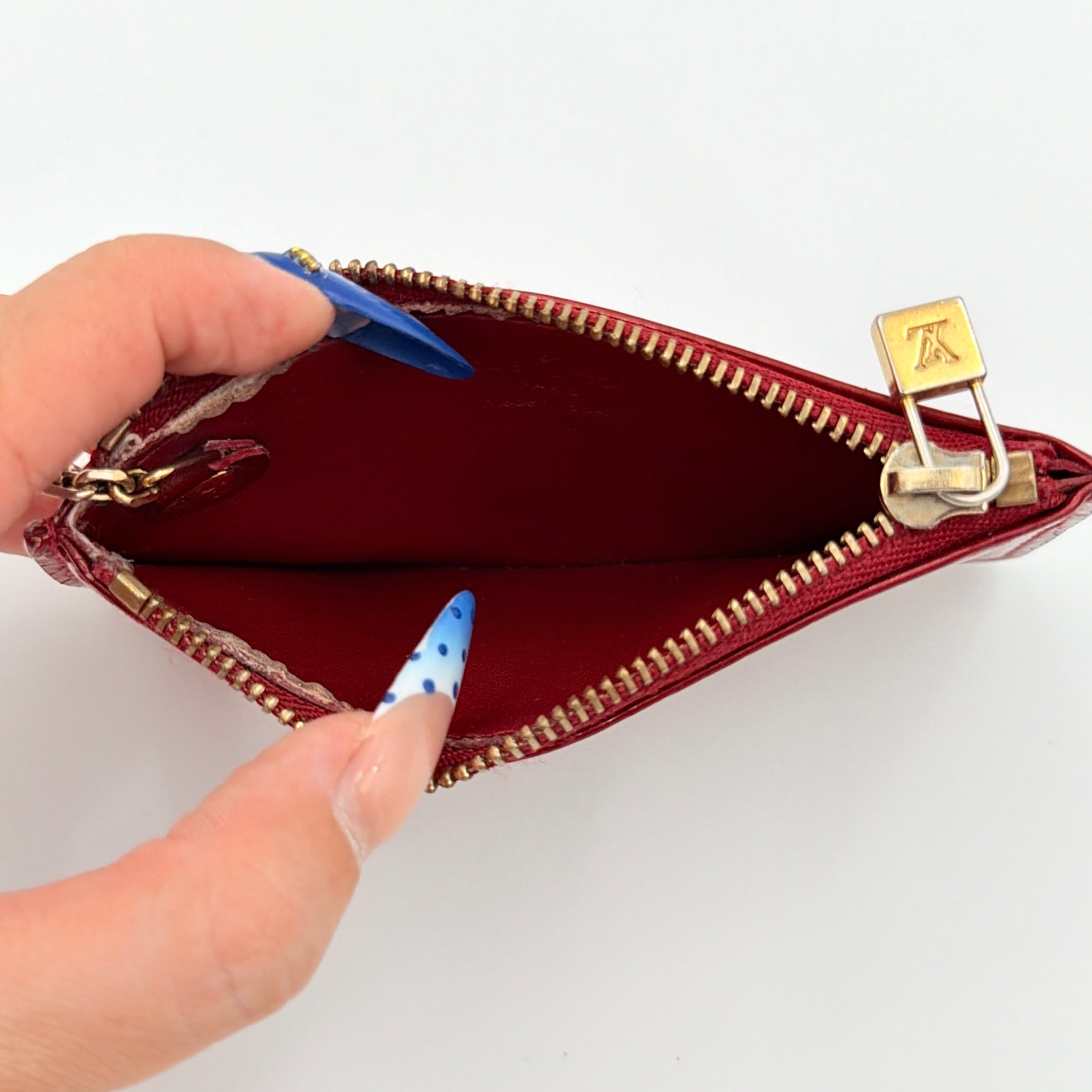 Louis Vuitton Vernis Coin Case in amethyst red patent leather with gold-tone key chain and zip closure, embossed with monogram pattern.