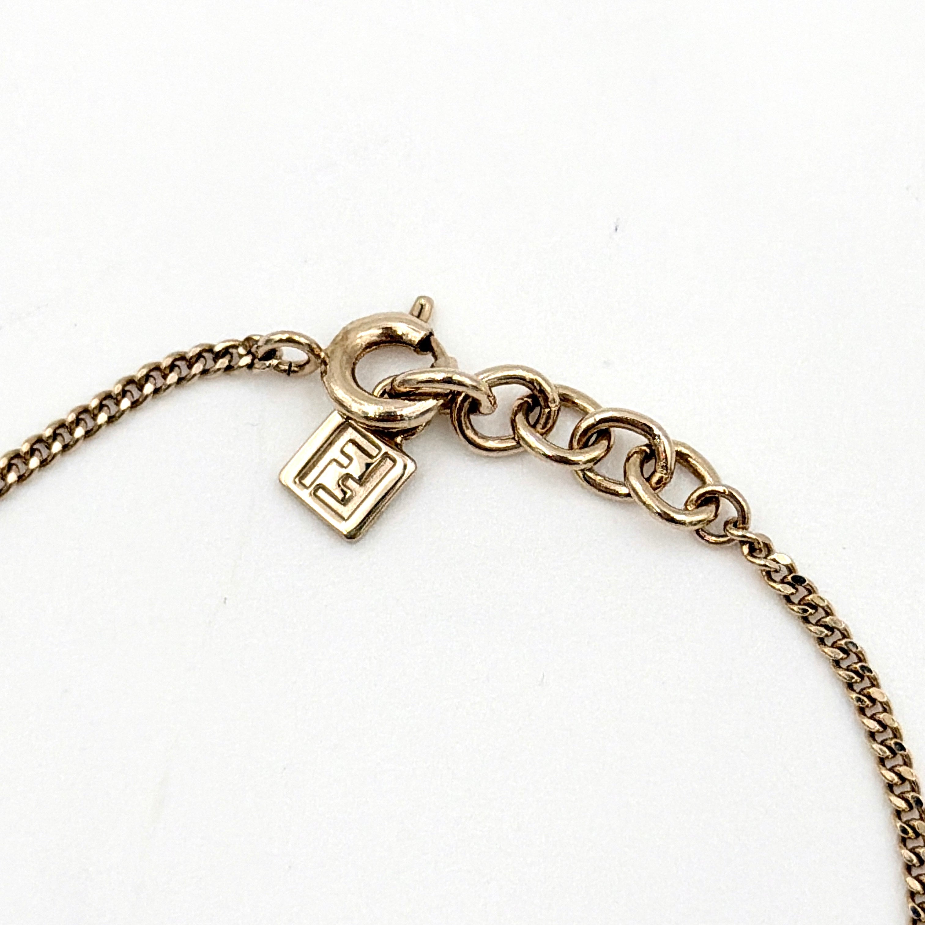 A gold-tone Fendi bracelet with a flowing logo script and adjustable chain, styled with a branded charm.