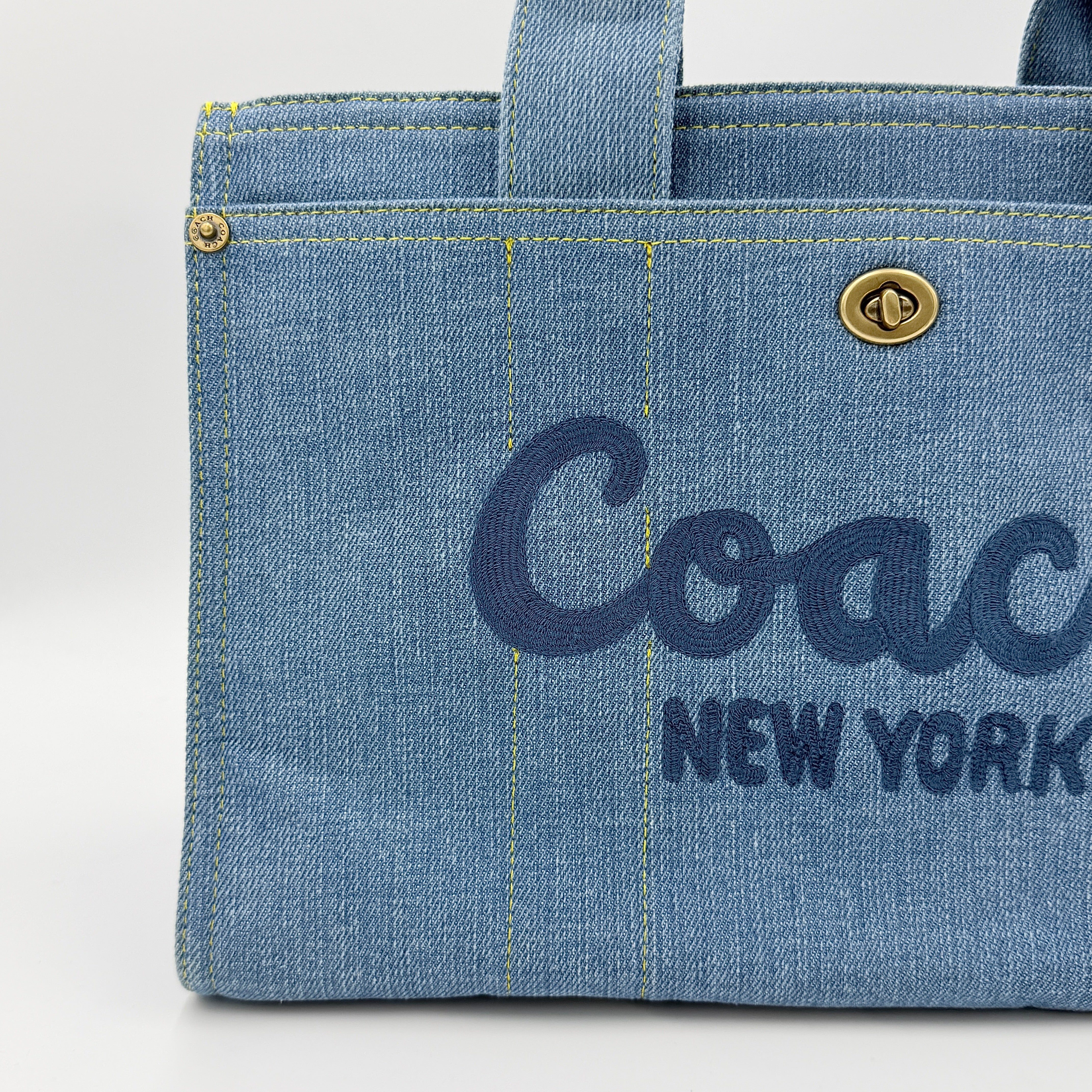 Coach denim 2Way Logo 20 Tote Bag in blue, embroidered with 'Coach New York', shown with detachable navy strap.