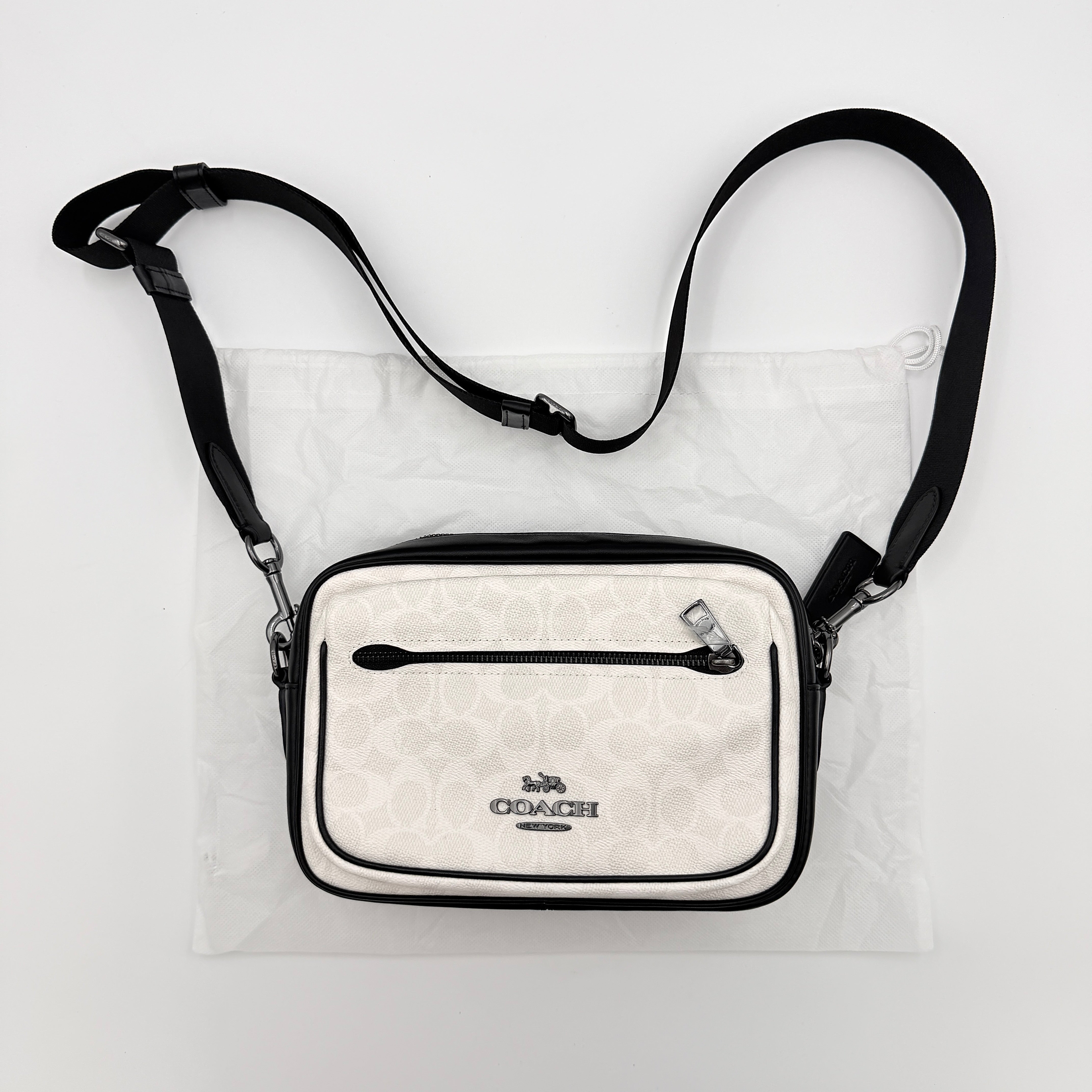 Coach Signature Elias Crossbody Bag in white canvas with black leather trim and silver hardware, styled with an adjustable black strap.