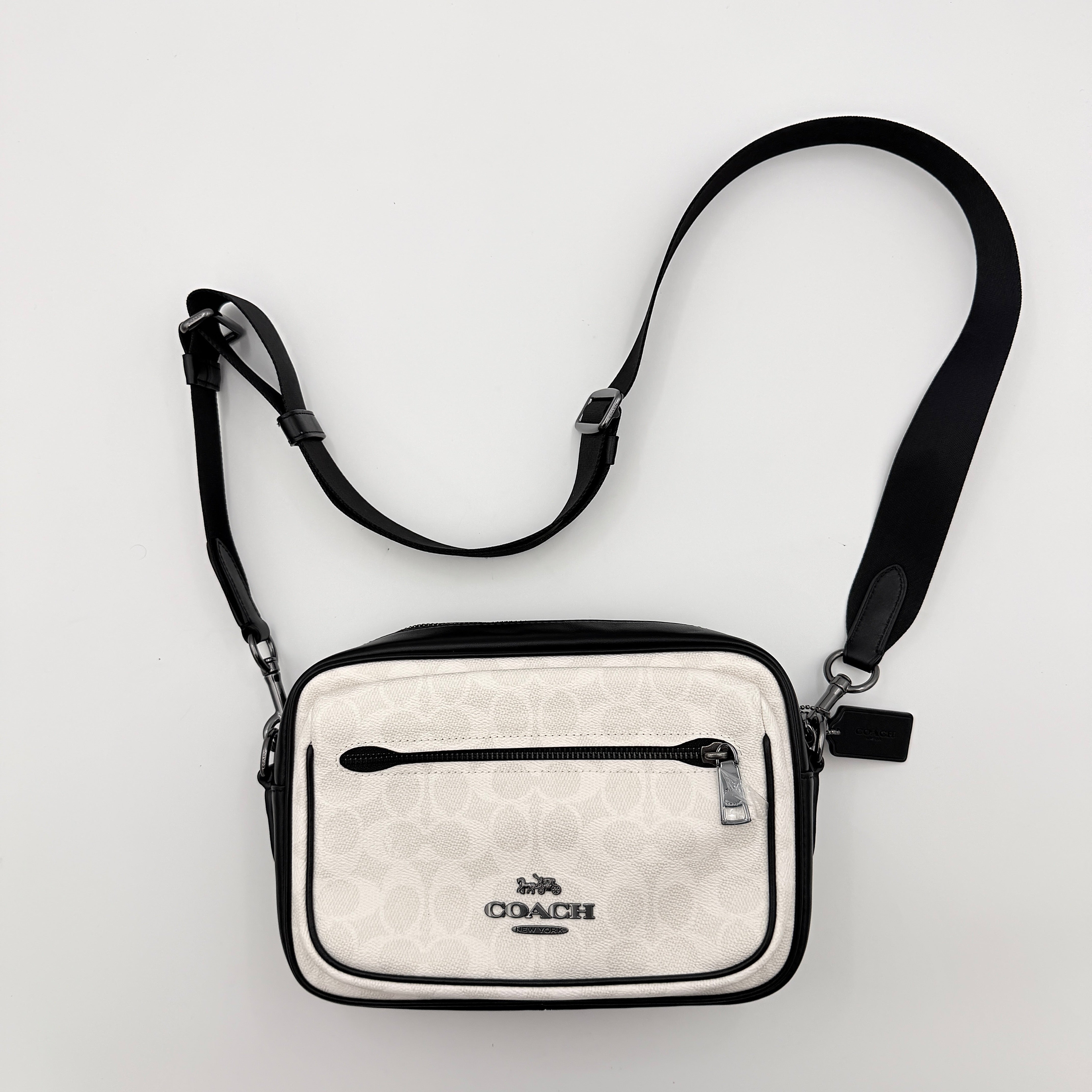 Coach Signature Elias Crossbody Bag in white canvas with black leather trim and silver hardware, styled with an adjustable black strap.
