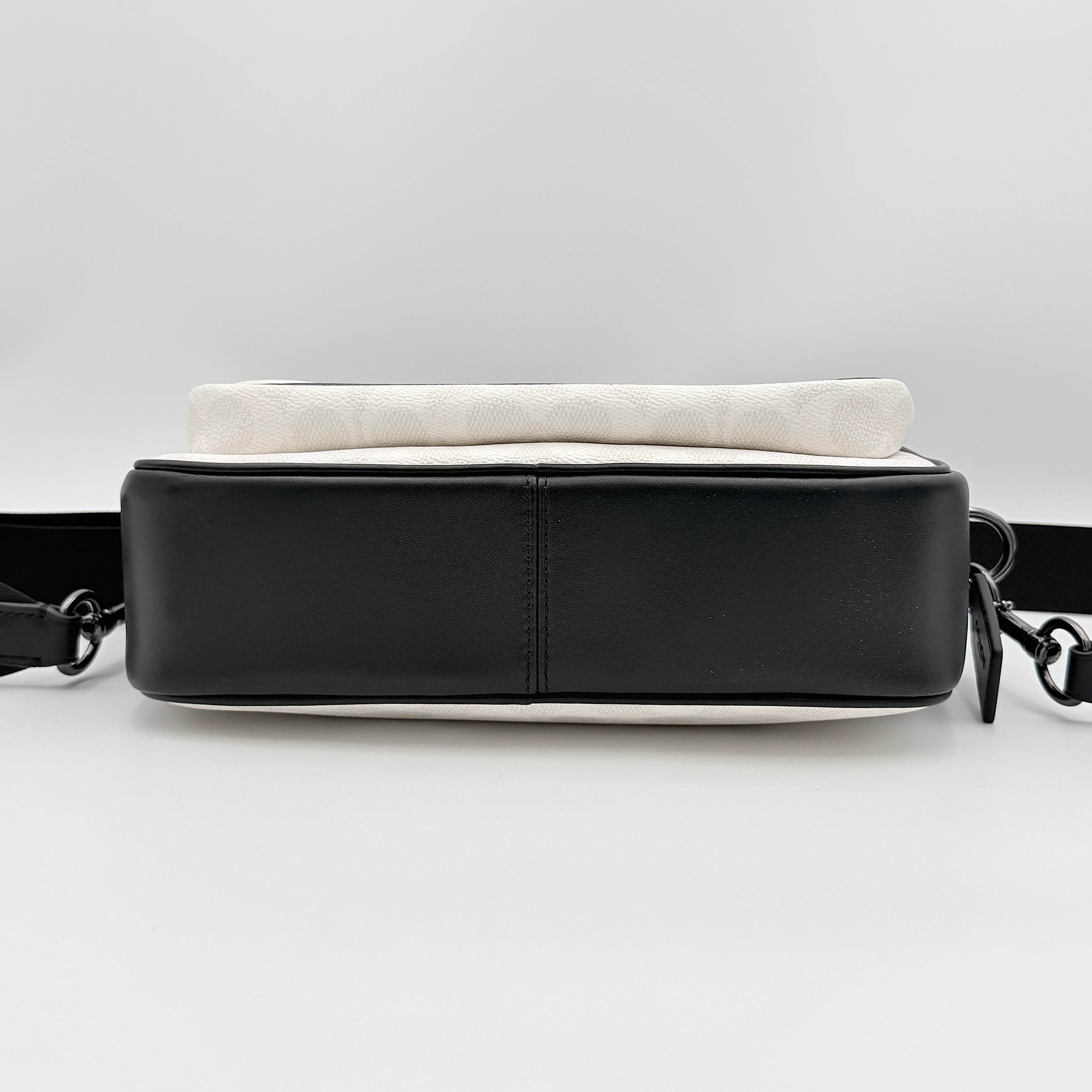 Coach Signature Elias Crossbody Bag in white canvas with black leather trim and silver hardware, styled with an adjustable black strap.