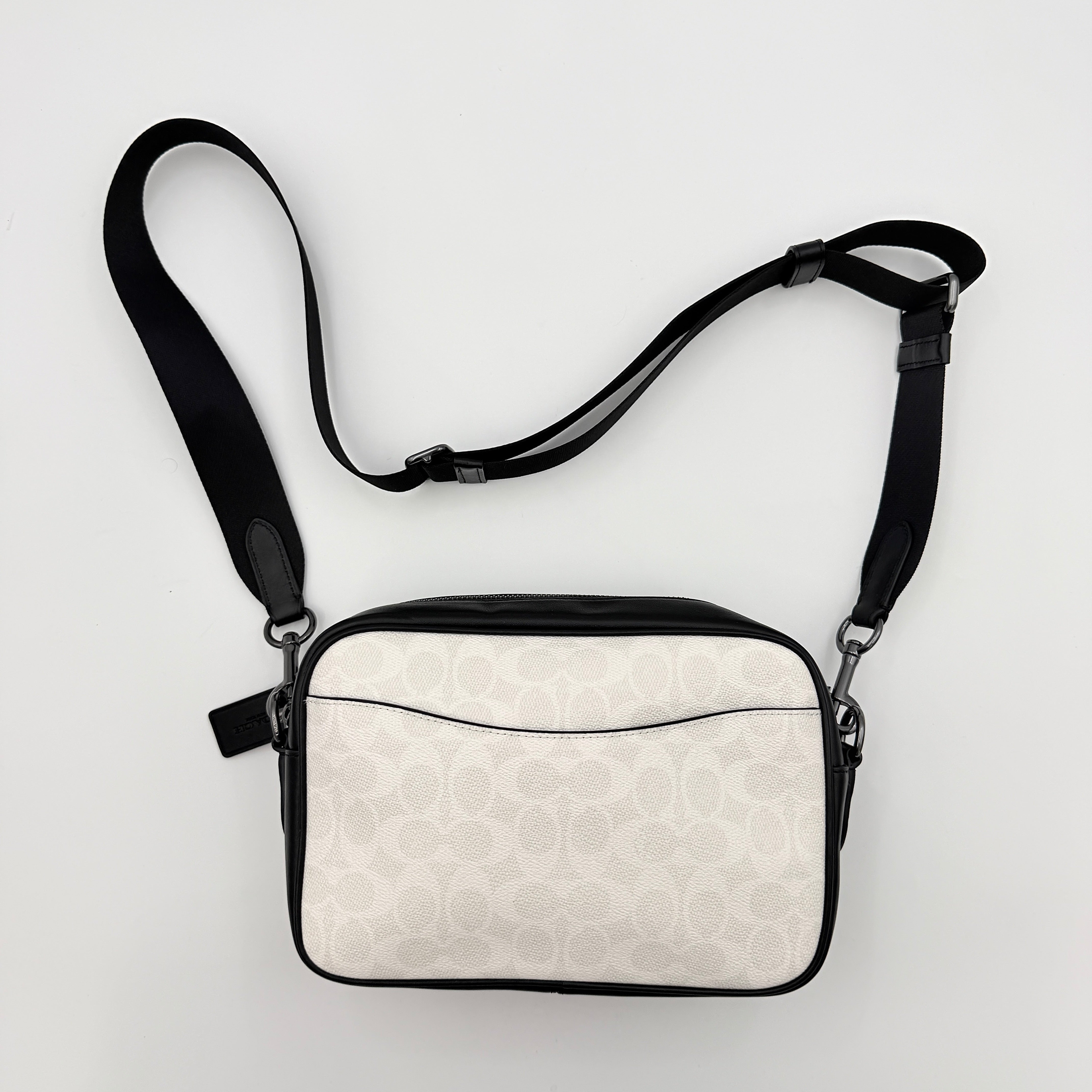 Coach Signature Elias Crossbody Bag in white canvas with black leather trim and silver hardware, styled with an adjustable black strap.