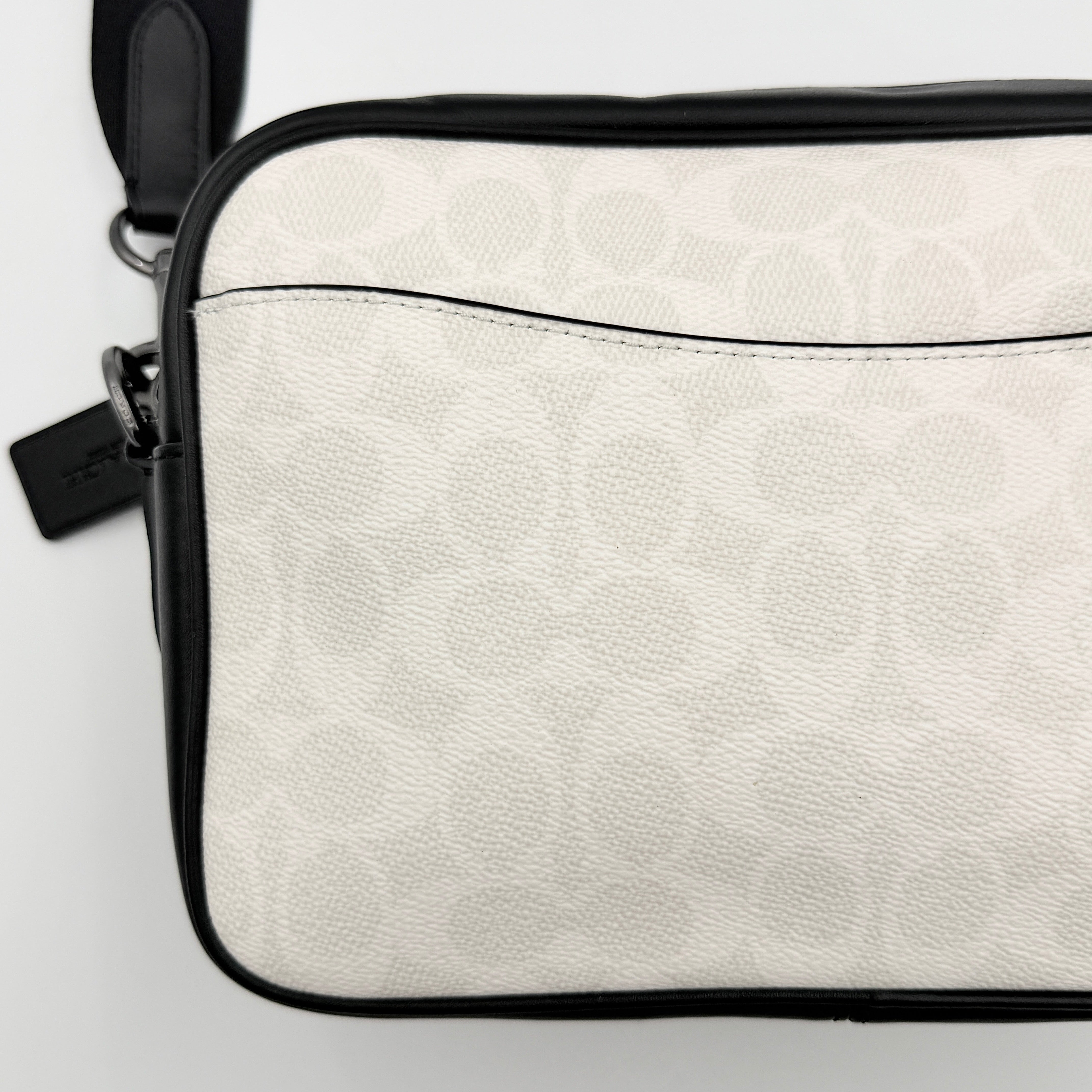 Coach Signature Elias Crossbody Bag in white canvas with black leather trim and silver hardware, styled with an adjustable black strap.