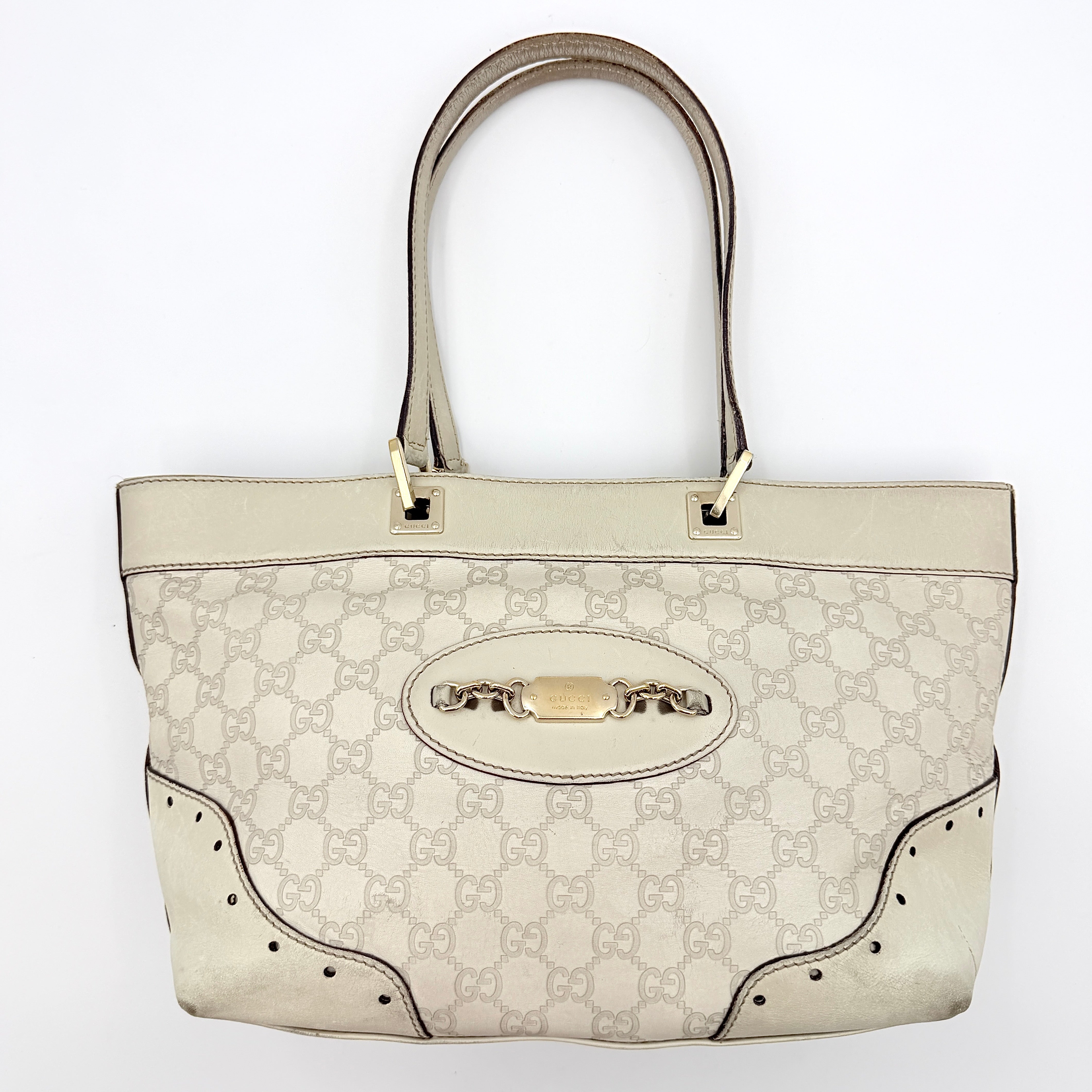 Cream Gucci GG Monogram Guccissima Punch Shoulder Bag with gold hardware, sculpted corners, and double top handles against a white background.