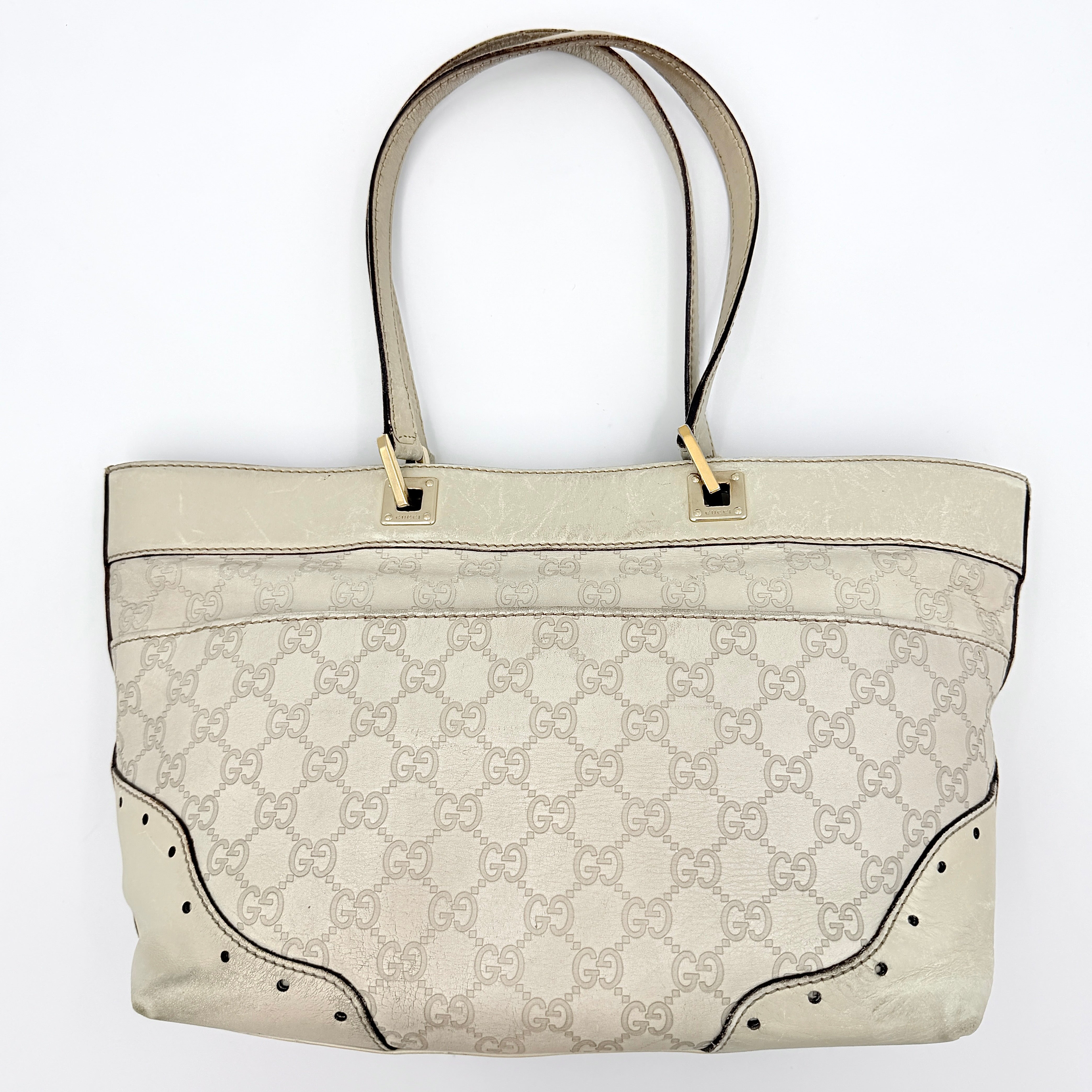 Cream Gucci GG Monogram Guccissima Punch Shoulder Bag with gold hardware, sculpted corners, and double top handles against a white background.