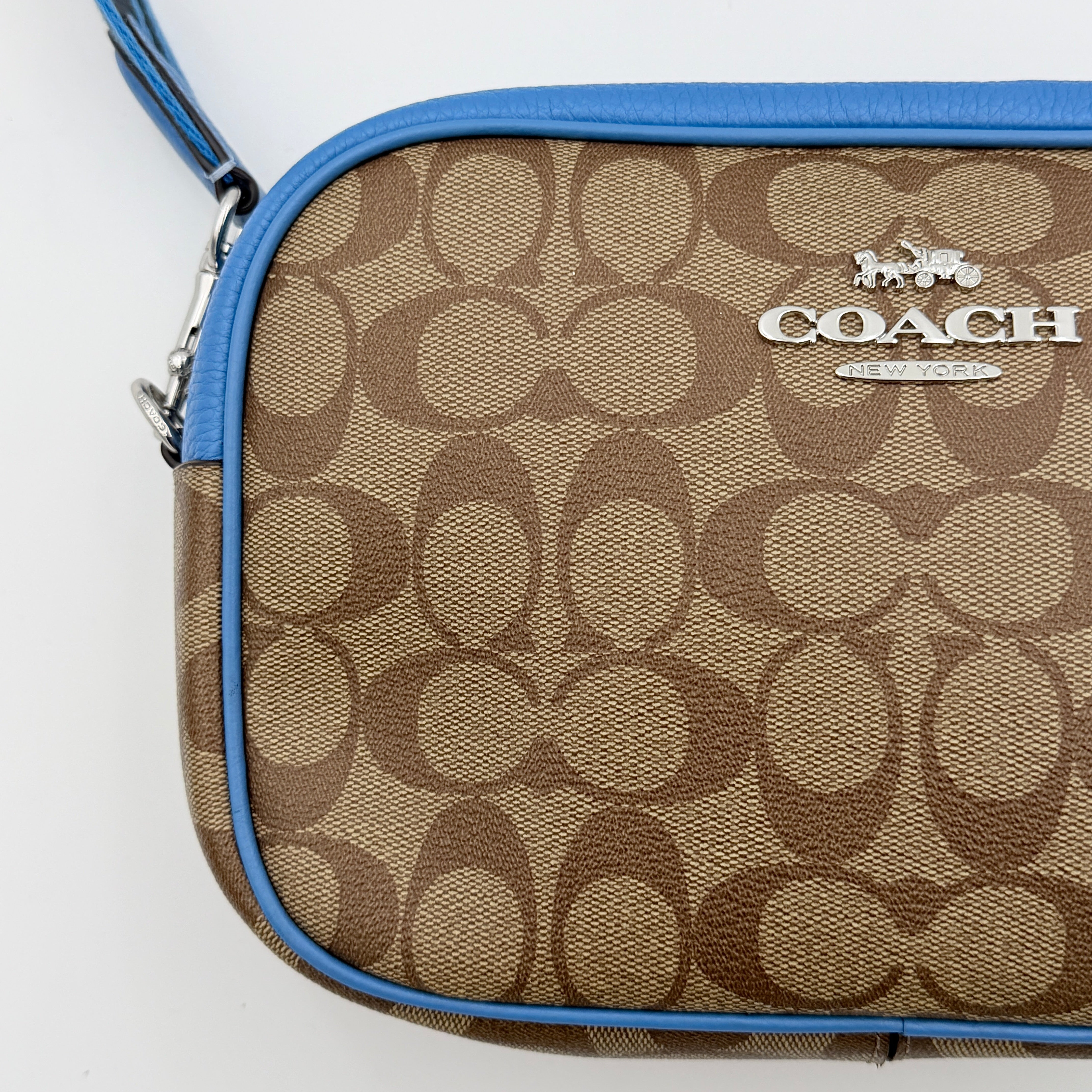 Coach Signature Jamie Crossbody Bag in beige and blue with bold logo webbing strap and blue leather trim, photographed against a white background.