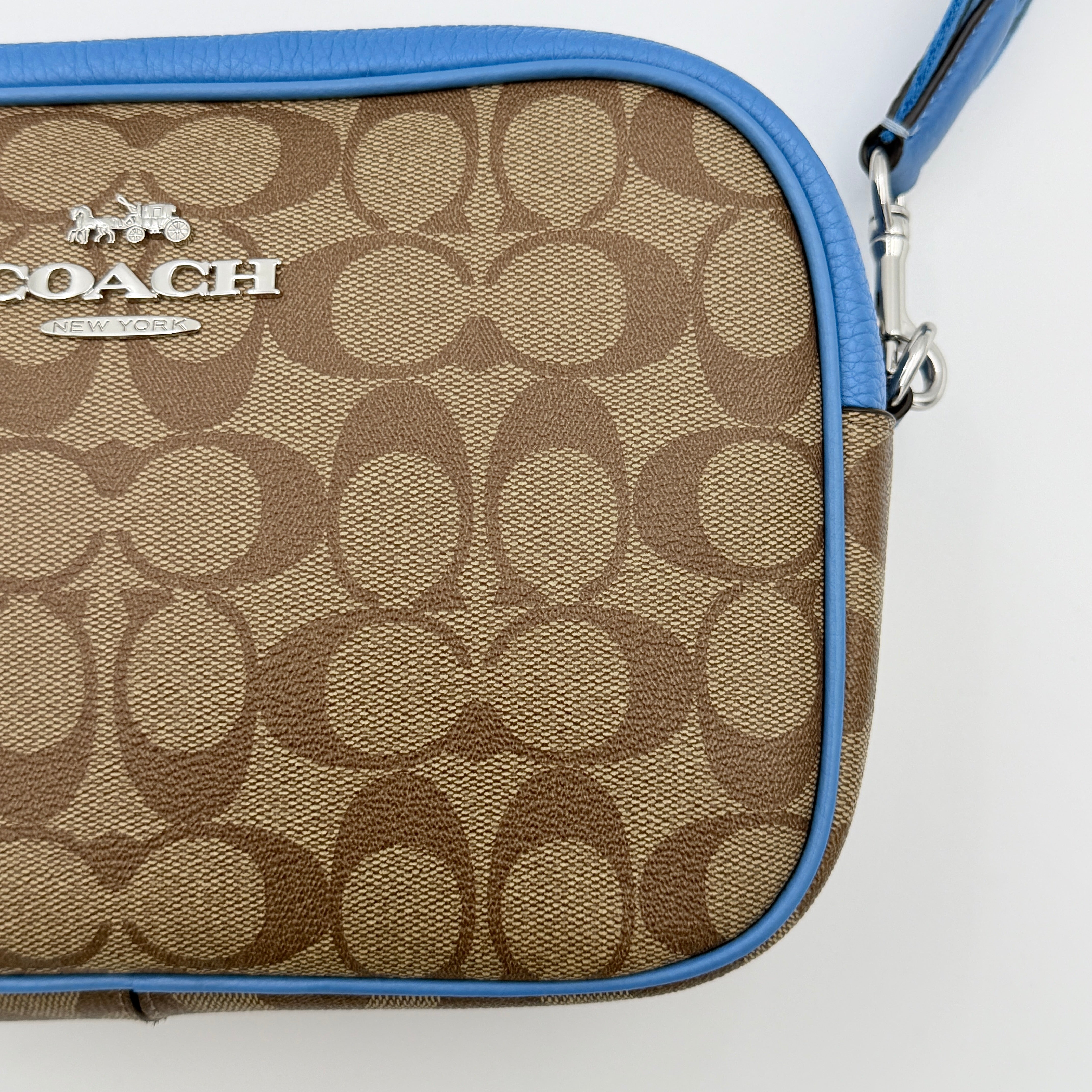 Coach Signature Jamie Crossbody Bag in beige and blue with bold logo webbing strap and blue leather trim, photographed against a white background.