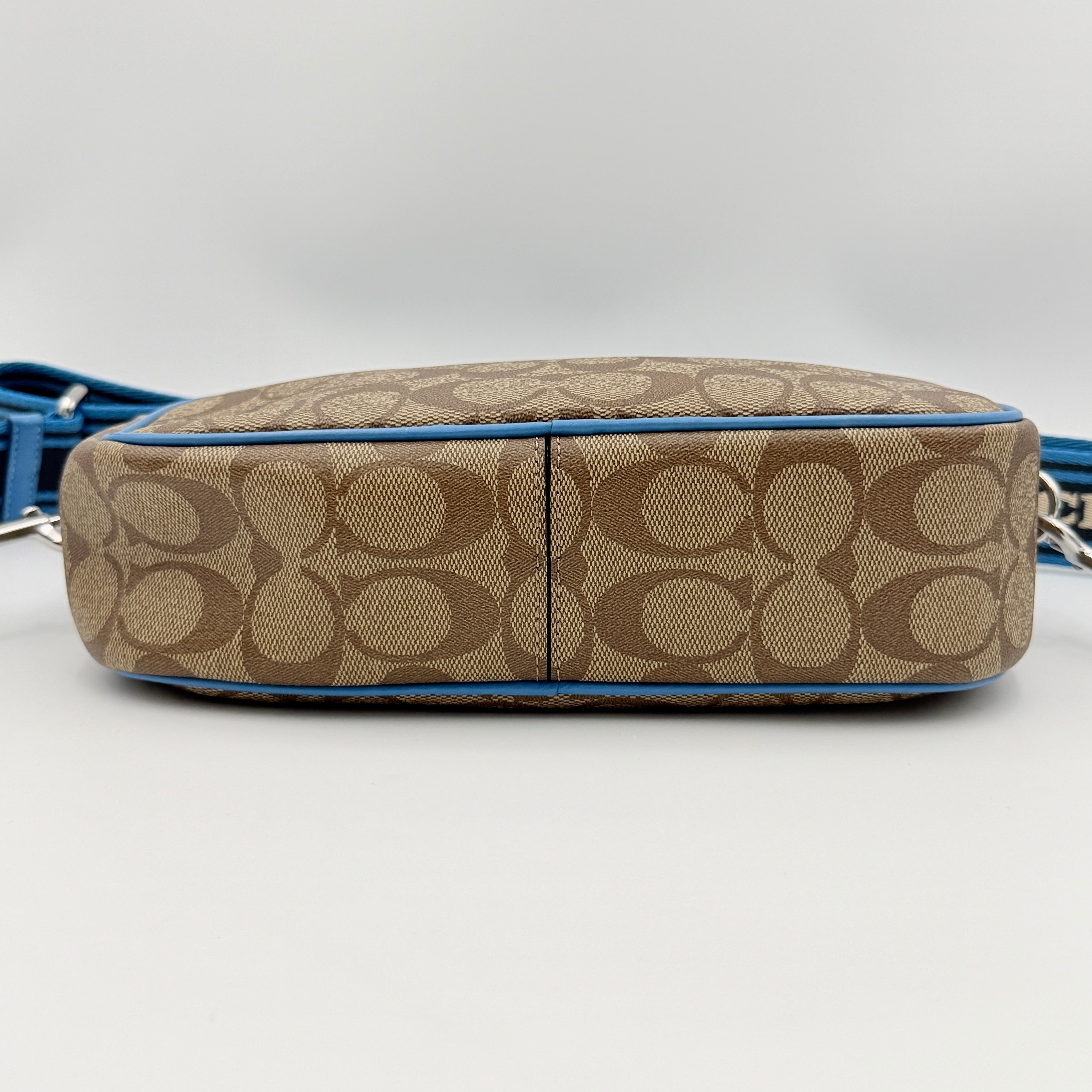 Coach Signature Jamie Crossbody Bag in beige and blue with bold logo webbing strap and blue leather trim, photographed against a white background.