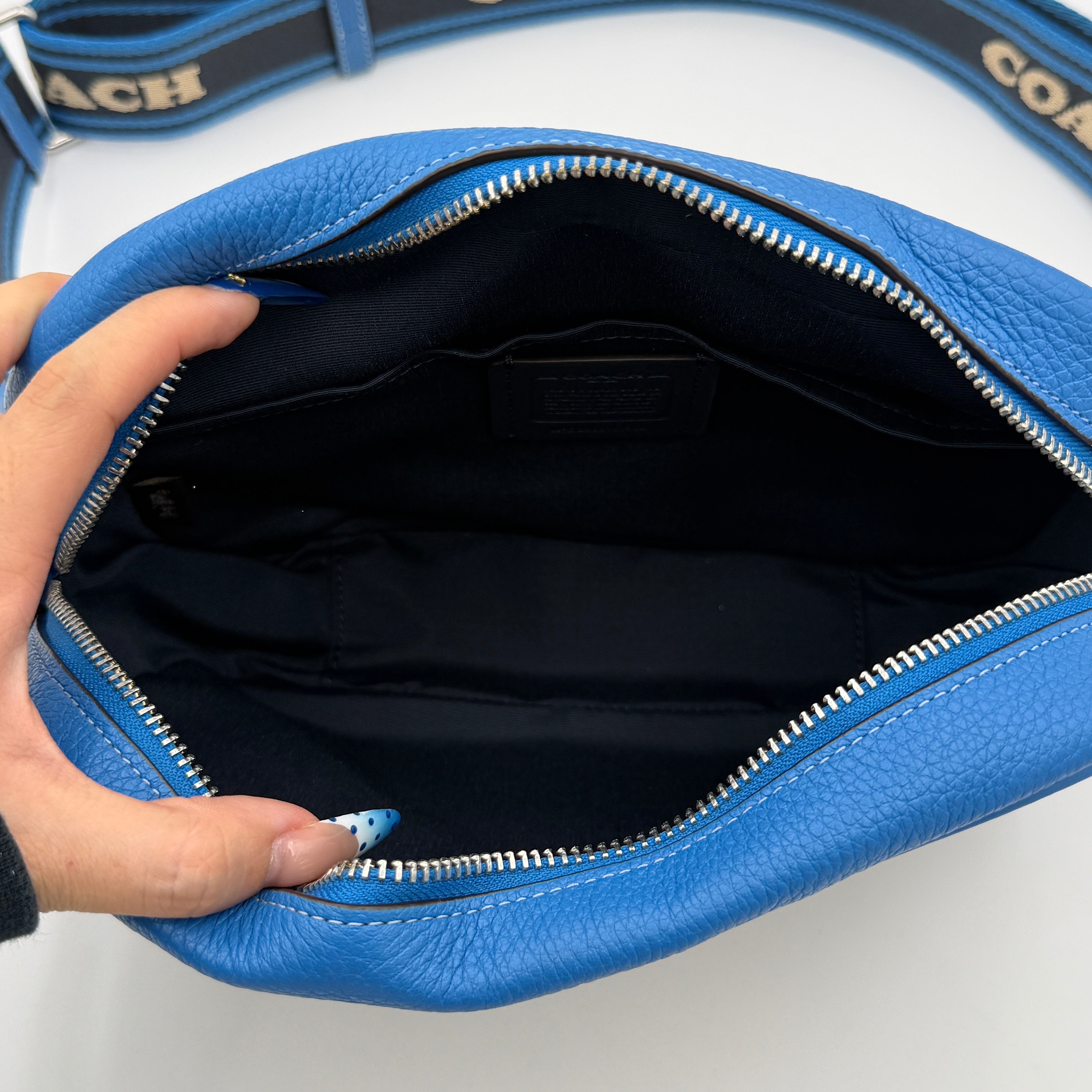 Coach Signature Jamie Crossbody Bag in beige and blue with bold logo webbing strap and blue leather trim, photographed against a white background.