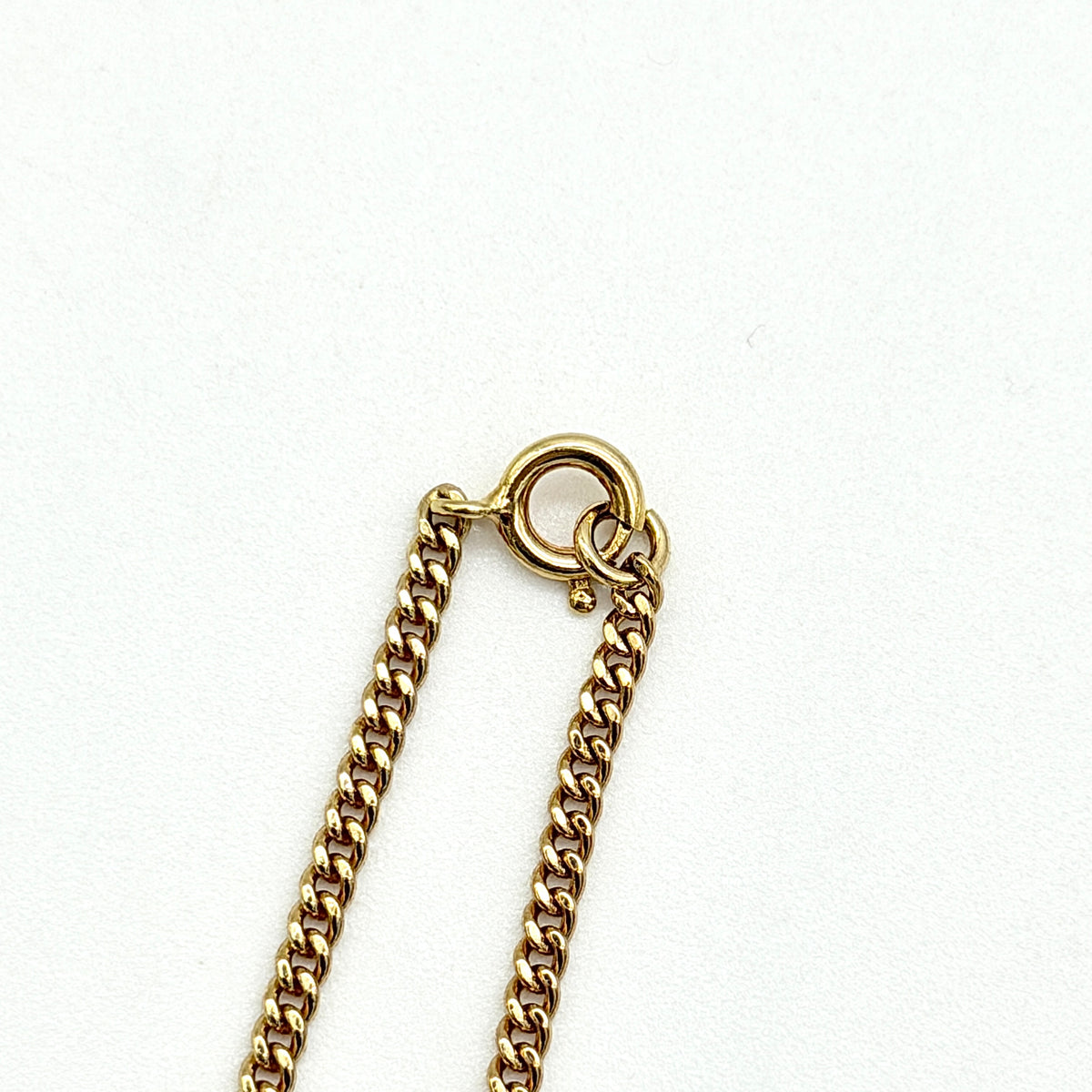 Dior gold-tone logo circle bracelet featuring a curb chain and textured central Dior emblem, photographed on a white background.