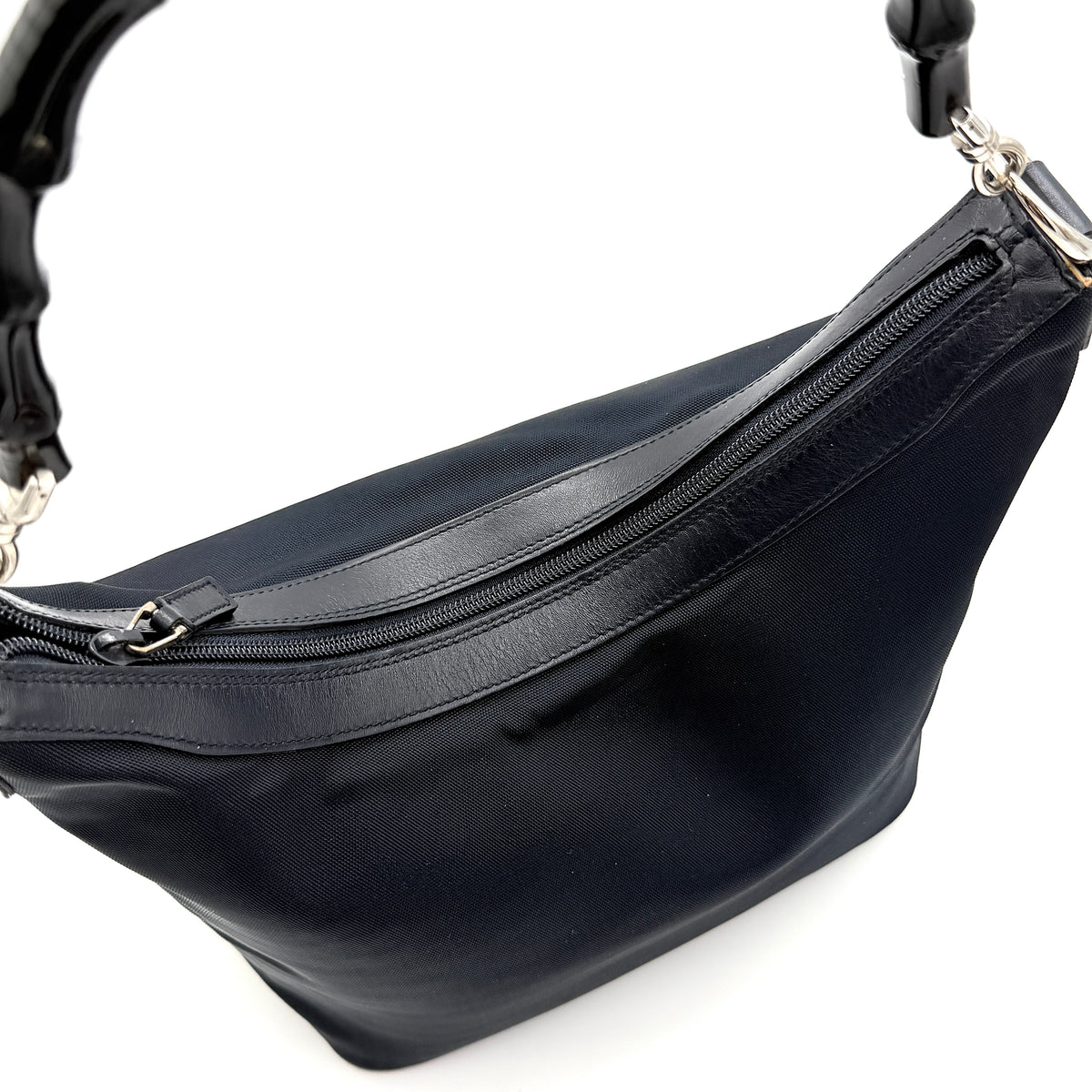 Gucci black nylon shoulder bag with bamboo handle and silver-tone hardware against a white background.