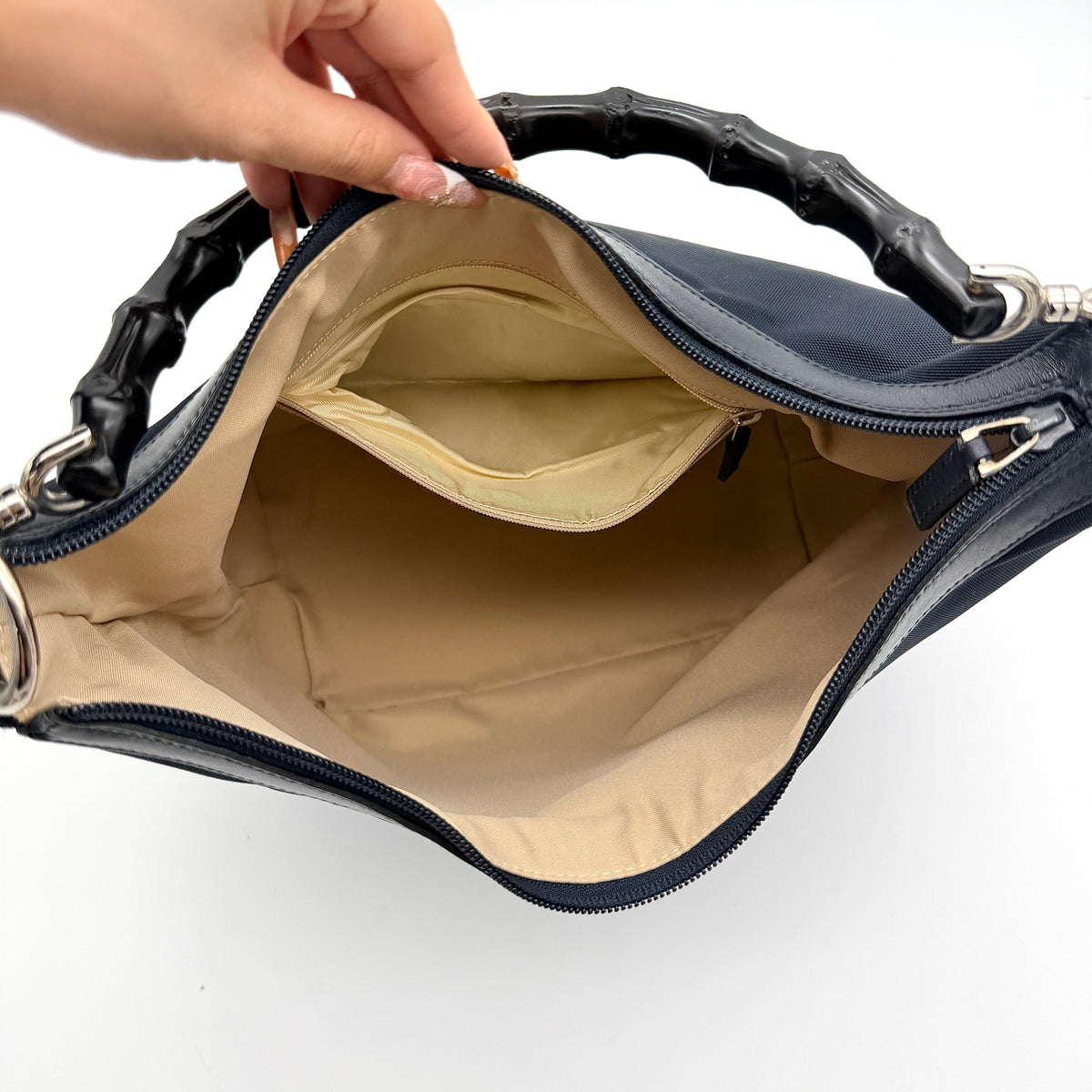 Gucci black nylon shoulder bag with bamboo handle and silver-tone hardware against a white background.