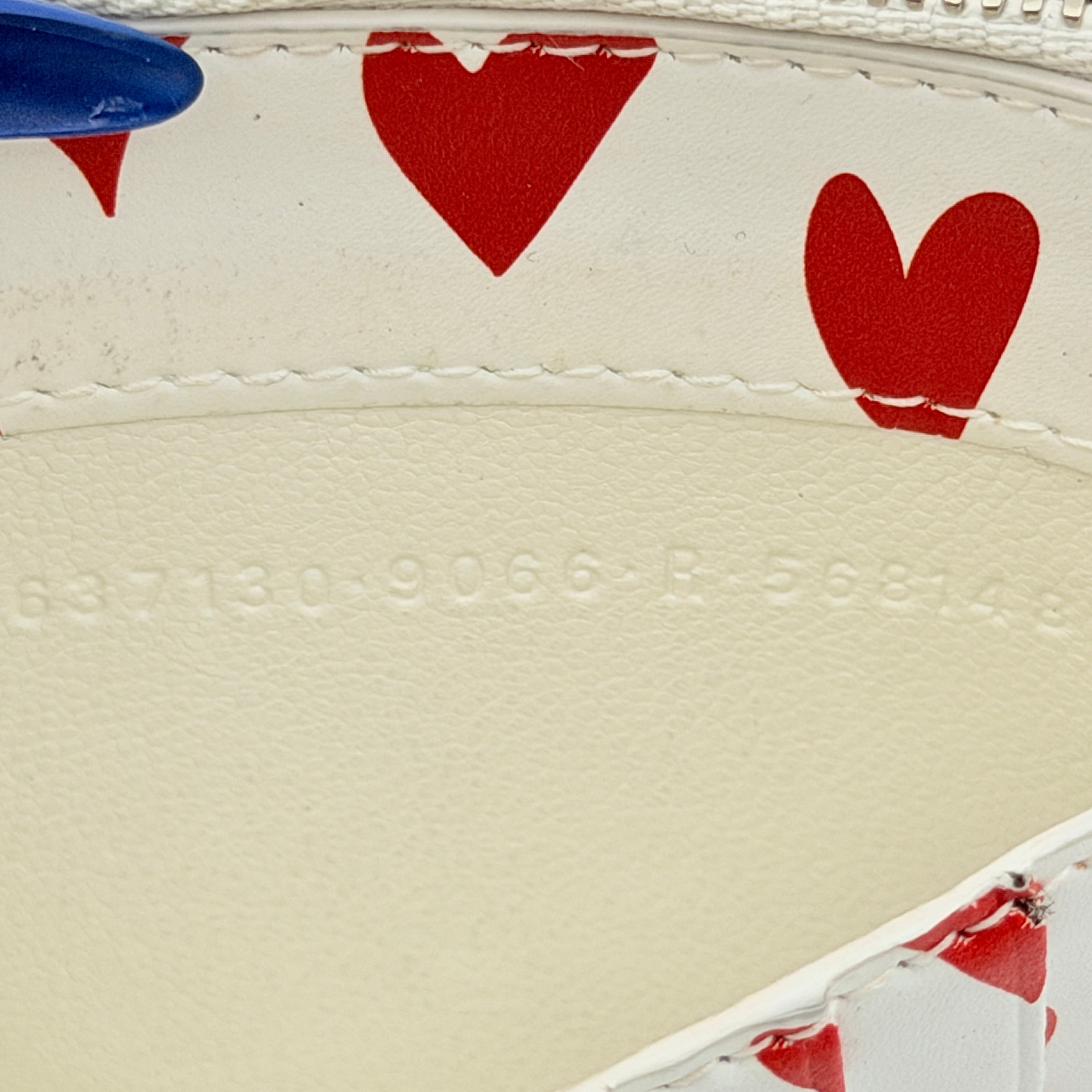 Balenciaga white leather card holder with playful red hearts and zip closure, set against a clean background.