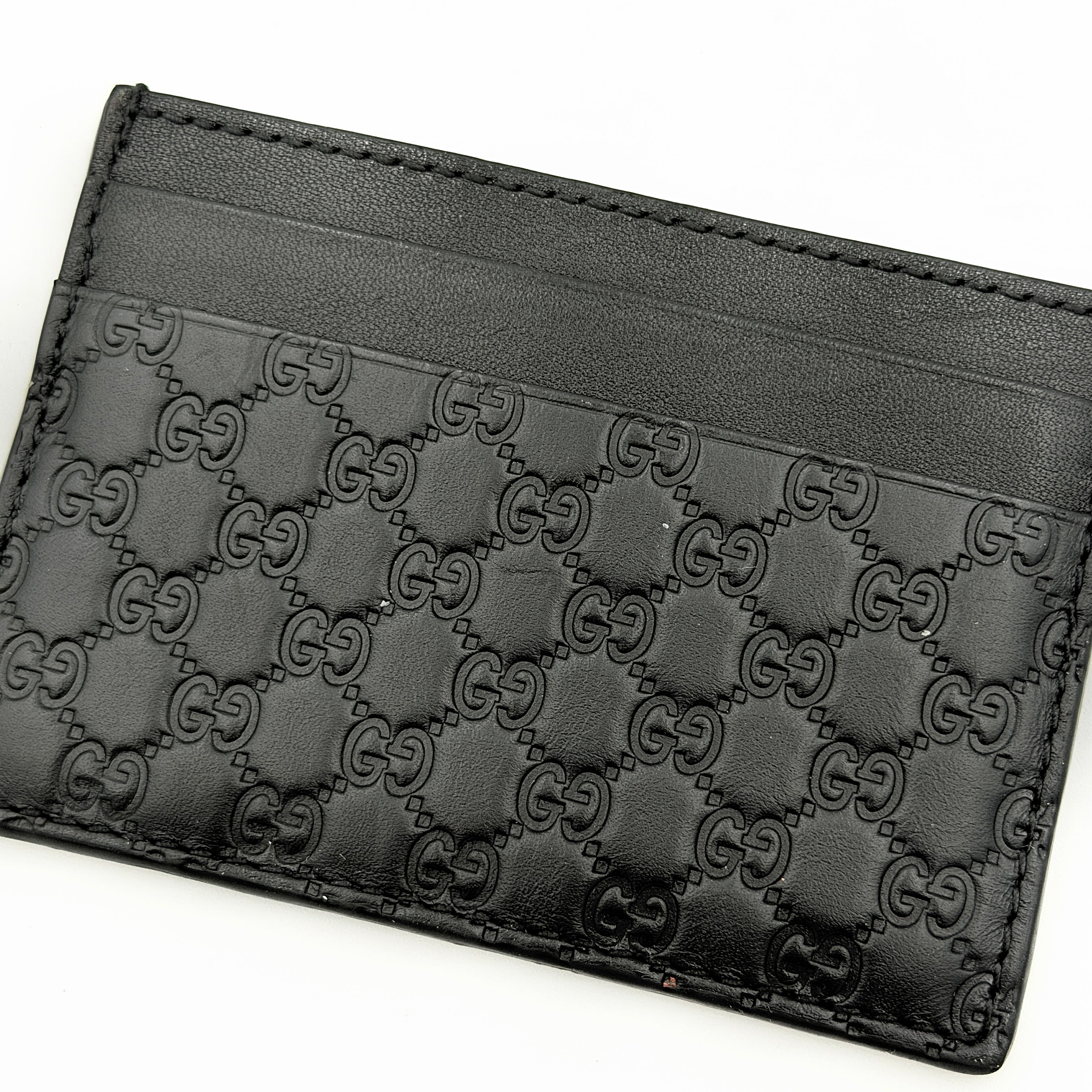 Gucci GG Microguccissima card holder in black leather with embossed micro GG motif, compact silhouette and refined finish.