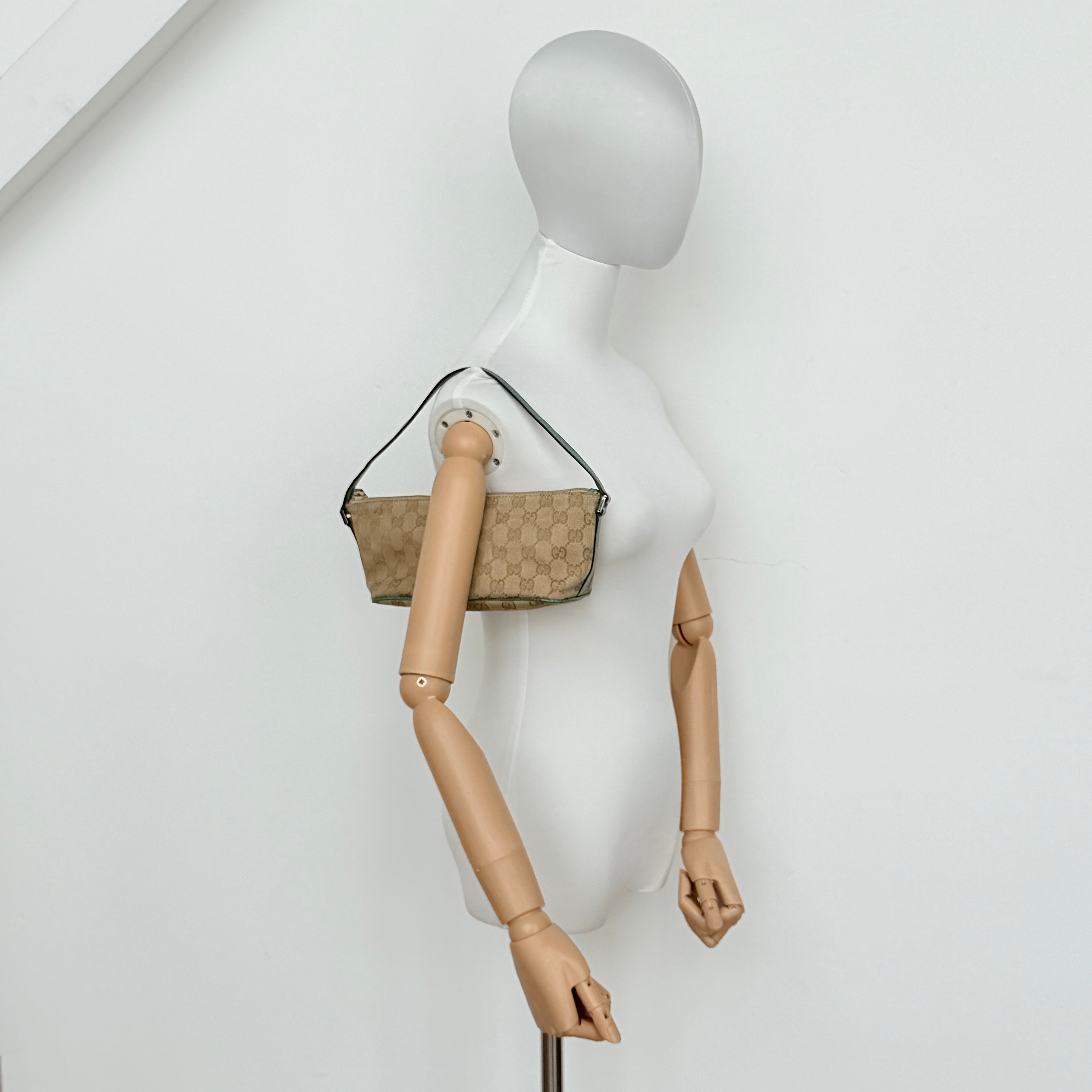 Gucci GG Monogram Pochette Boat Shoulder Bag in beige canvas with green leather trim and a structured, boat-shaped silhouette.