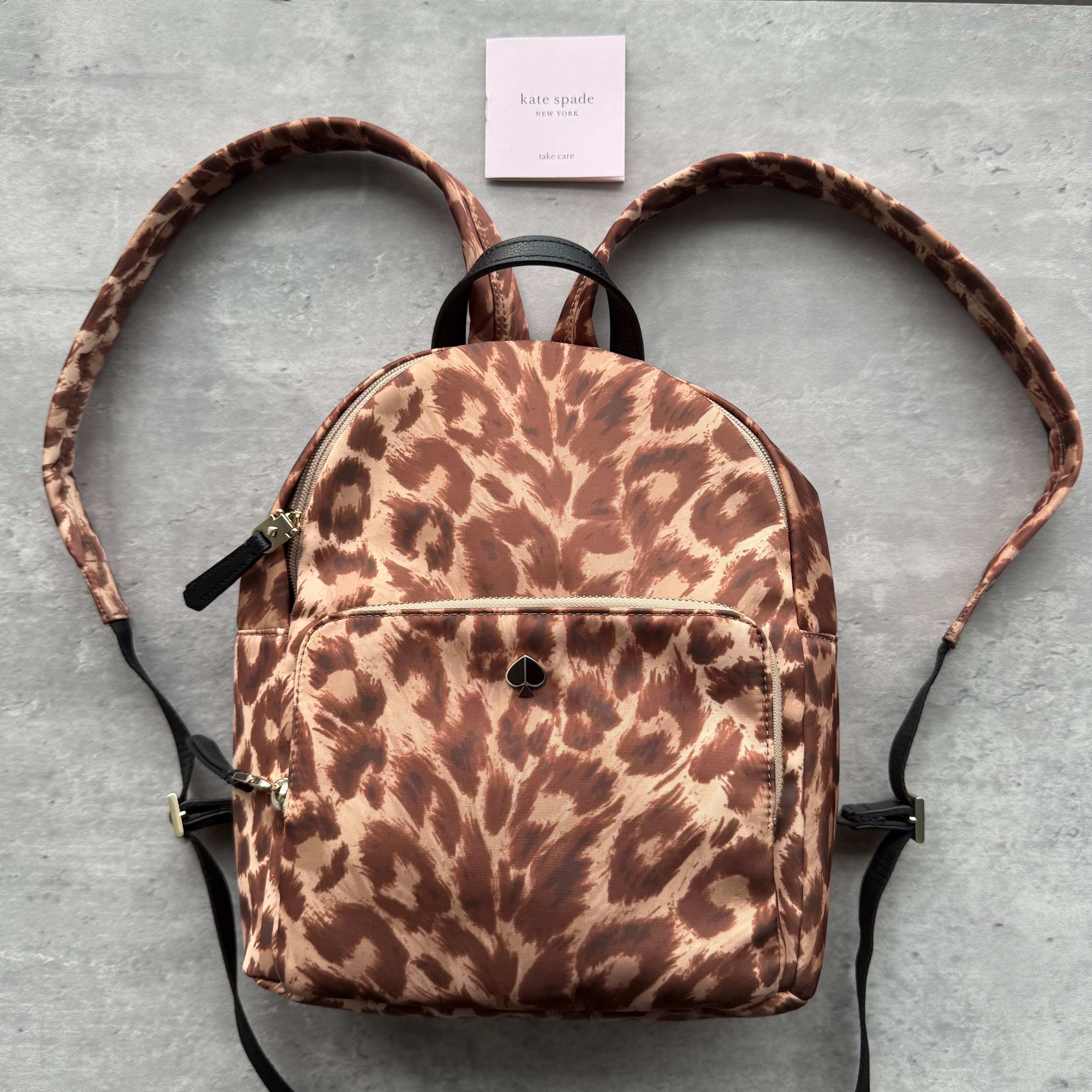 Kate Spade Taylor Leopard Print Nylon Backpack in brown tones with gold-tone hardware, front zip pocket, and adjustable straps.