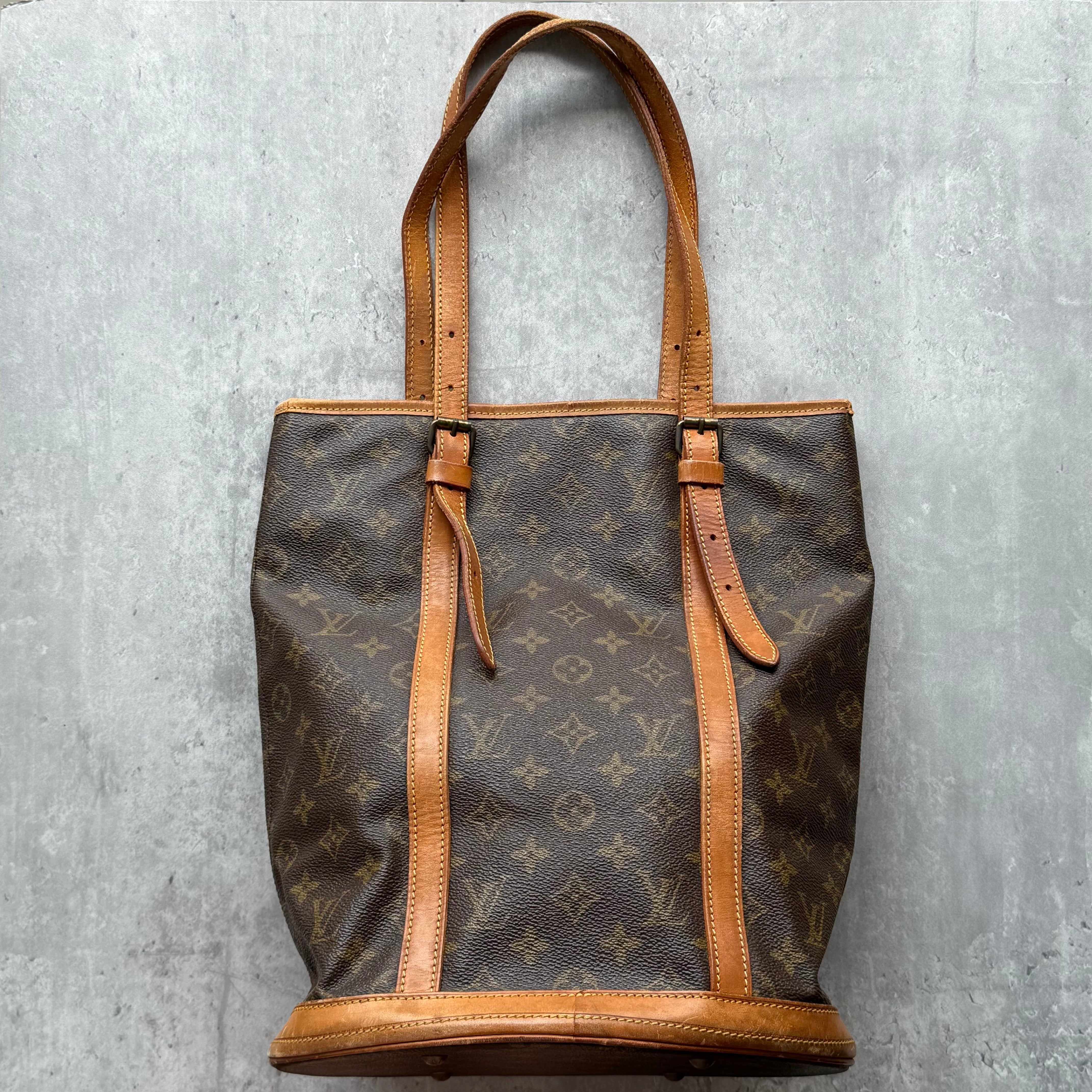 Louis Vuitton Monogram Bucket GM Shoulder Bag in brown coated canvas with Vachetta leather trim and dual straps.