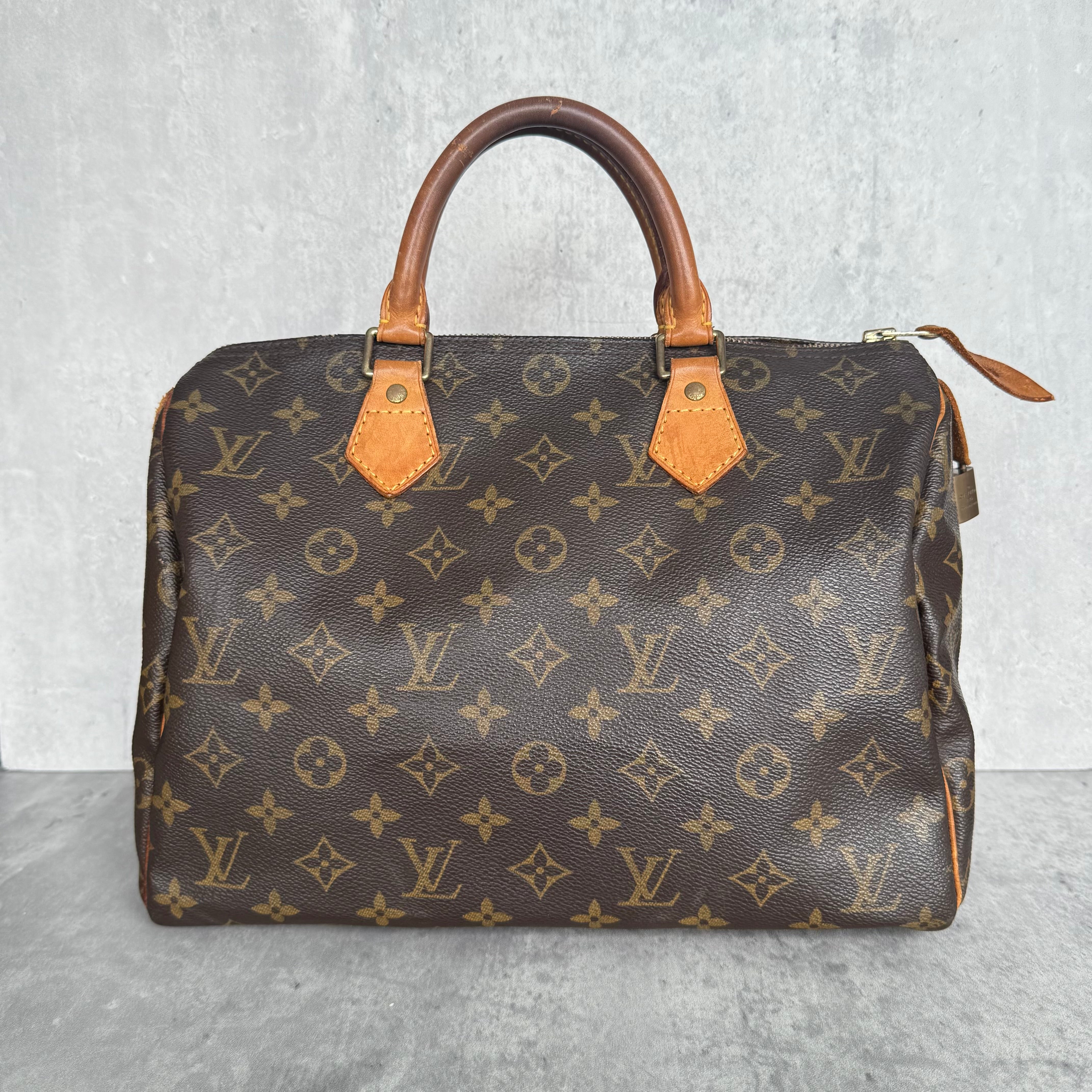 Louis Vuitton Monogram Speedy 30 Handbag in brown, crafted from monogram canvas with vachetta leather trim, gold-tone hardware, and LV key lock detail.