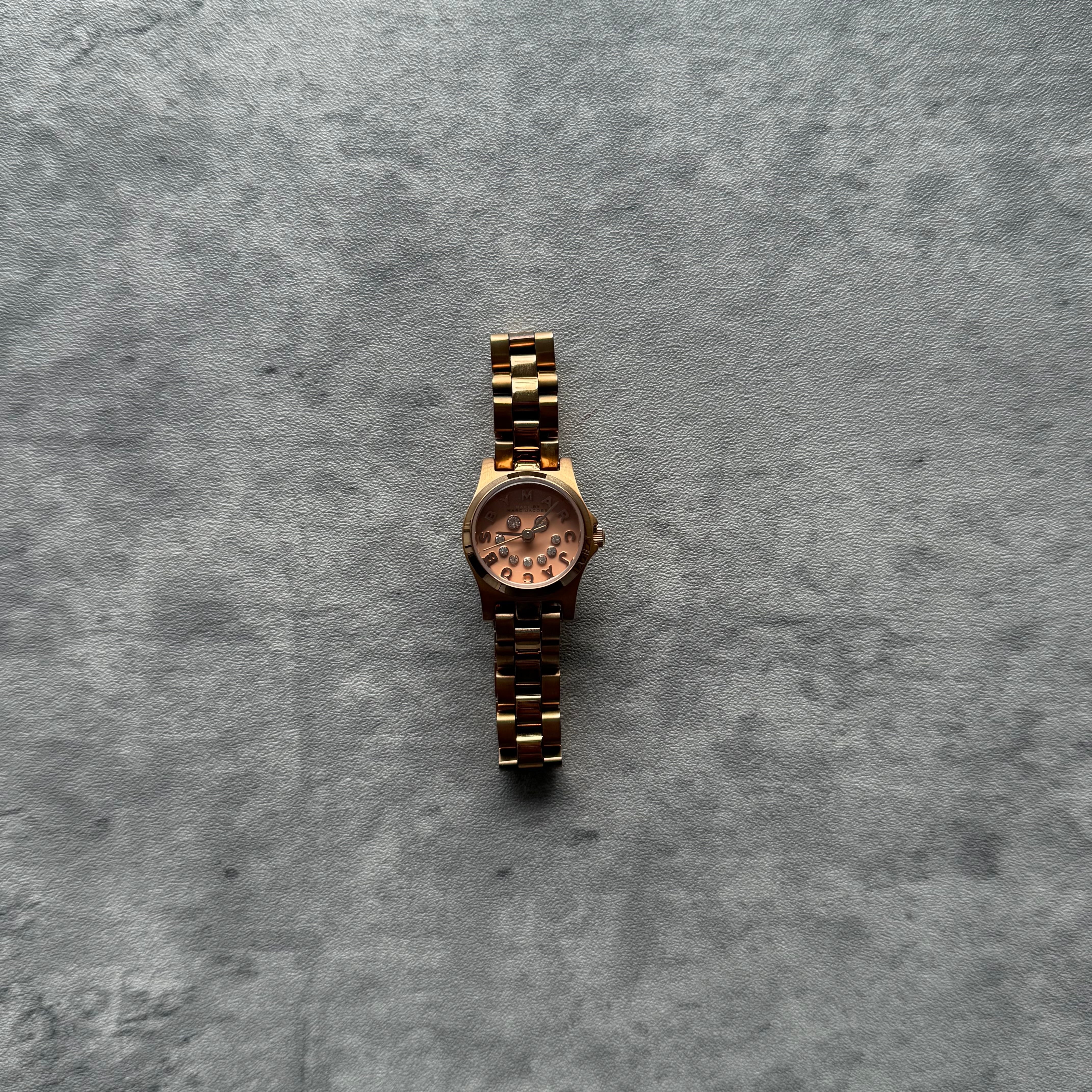Marc Jacobs Rose Gold Watch with light pink dial, crystal hour markers, and stainless steel link bracelet.