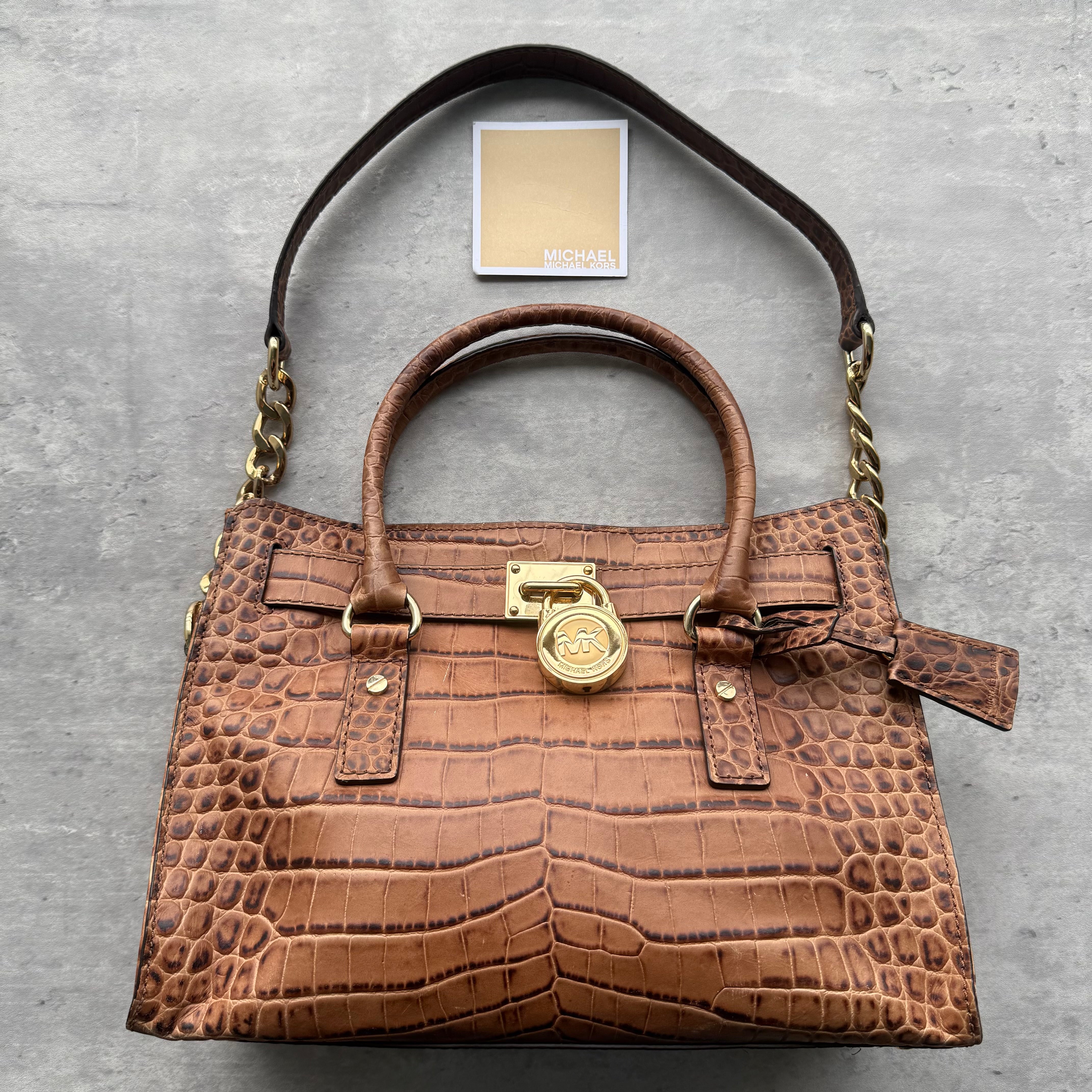 Michael Kors Hamilton Croc-Embossed Leather Handbag in brown with gold-tone MK padlock detail, dual top handles, chain-accented shoulder strap, and organized interior.