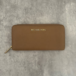 Michael Kors Jet Set Travel Zip-Around Saffiano Leather Continental Wallet in brown, featuring a gold-tone MK logo and zip-around closure.