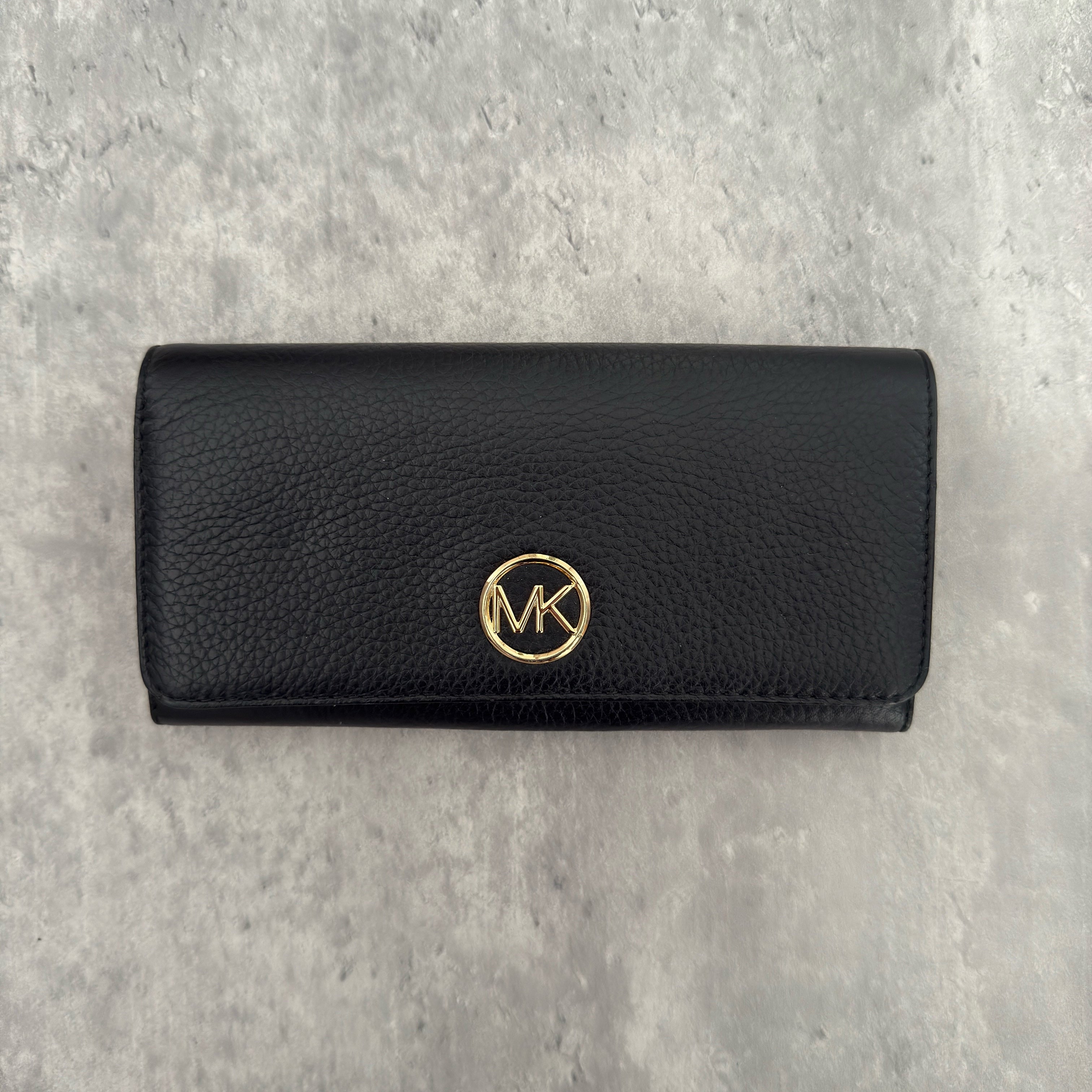 Michael Kors MK Gold Logo Bifold Long Wallet in black pebbled leather, featuring a structured silhouette with a gold-tone MK logo and a snap button closure.