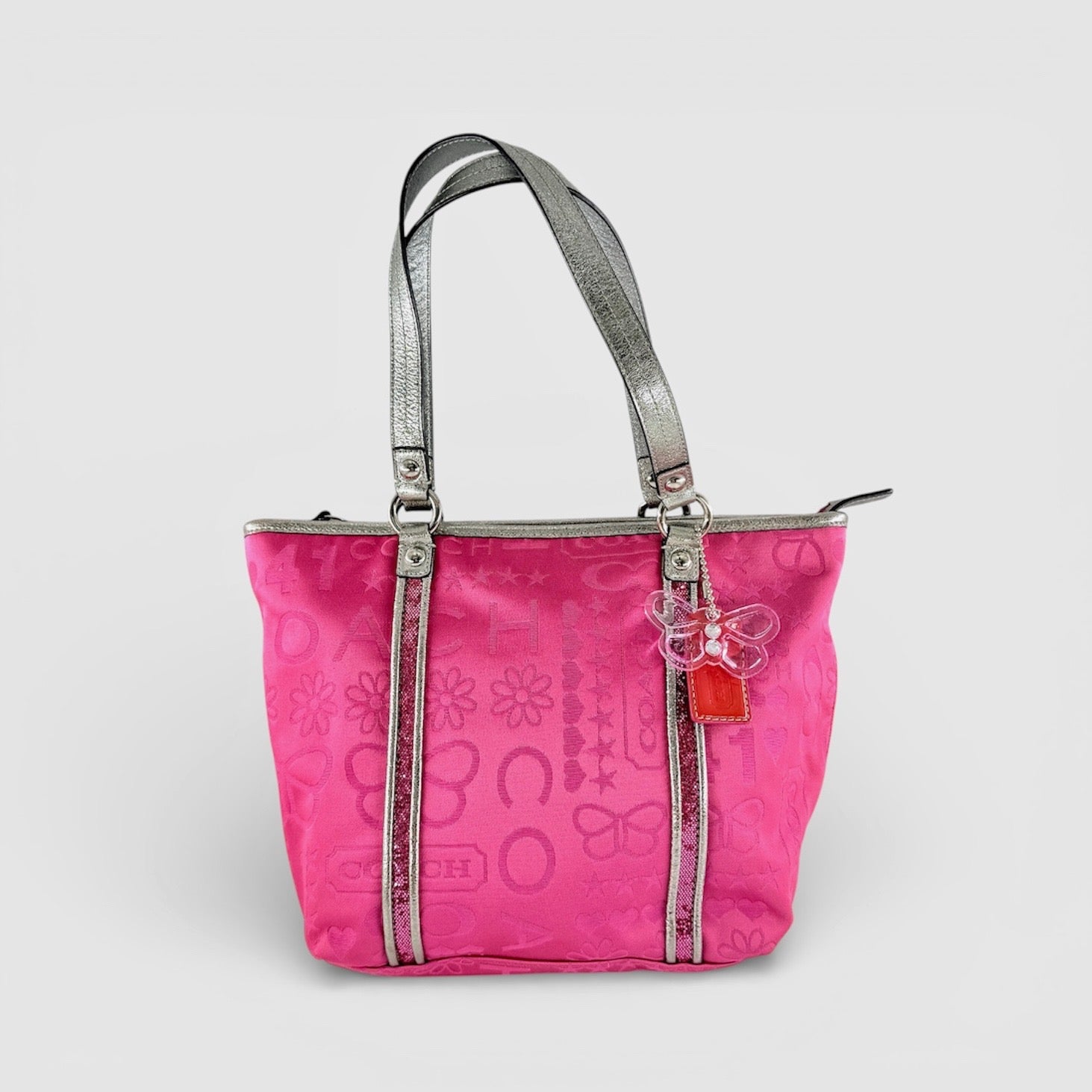 Coach Poppy Bandana Glitter Graffiti Tote Bag in vibrant pink with metallic silver handles, adorned with glitter accents and butterfly charm.