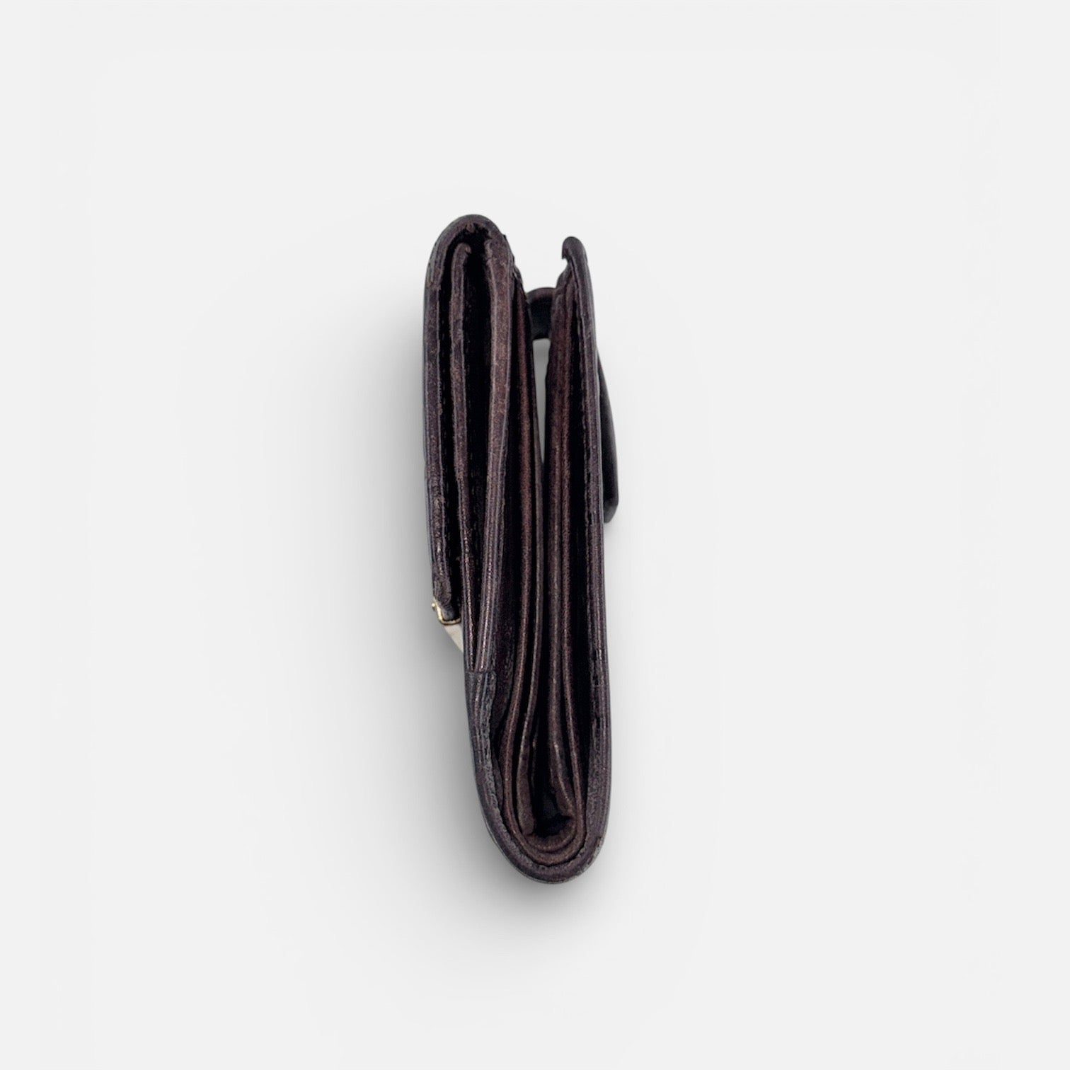 Front-facing Gucci GG Monogram Guccissima wallet in deep brown embossed leather with gold-tone bar accent.