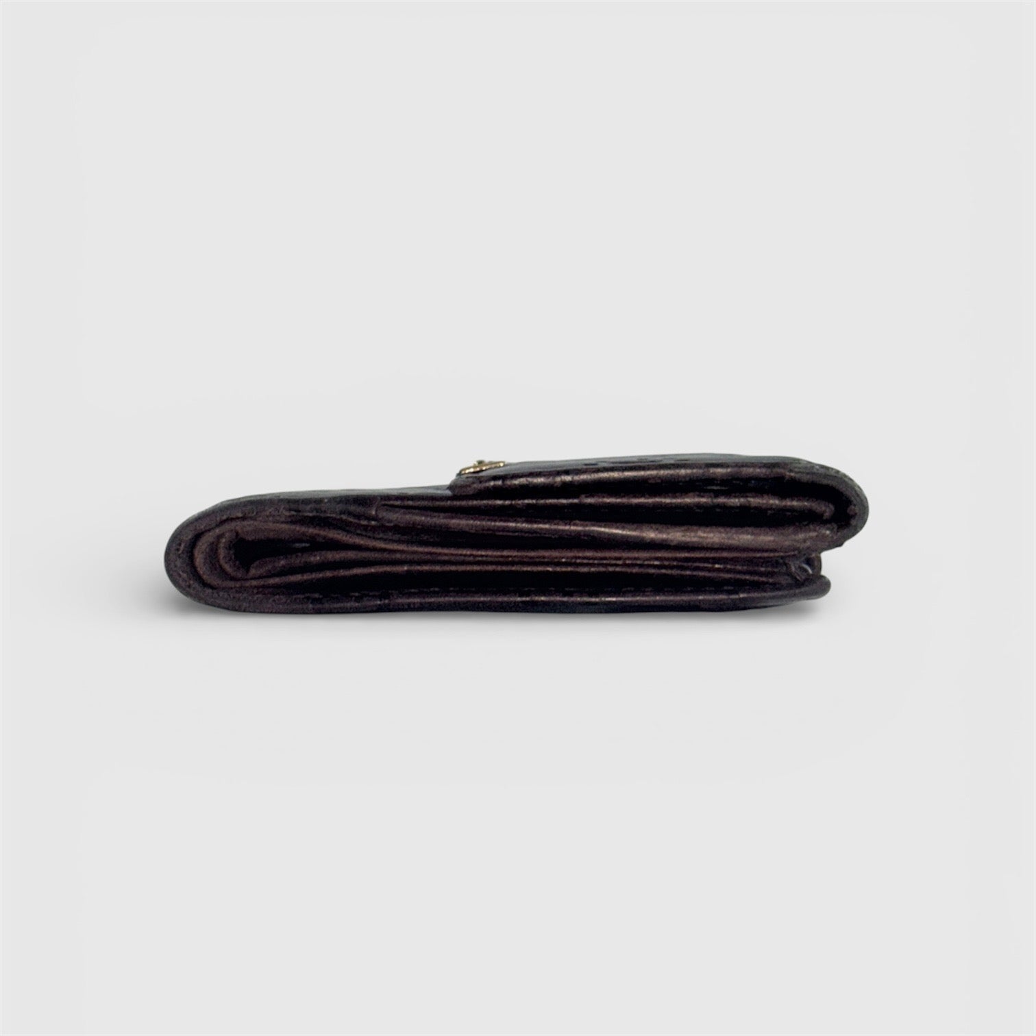 Front-facing Gucci GG Monogram Guccissima wallet in deep brown embossed leather with gold-tone bar accent.