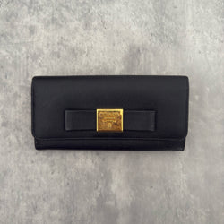 Prada Milano Black Saffiano Leather Ribbon Bow Long Wallet, crafted from textured black Saffiano leather with a gold-tone logo plaque and ribbon bow detail.