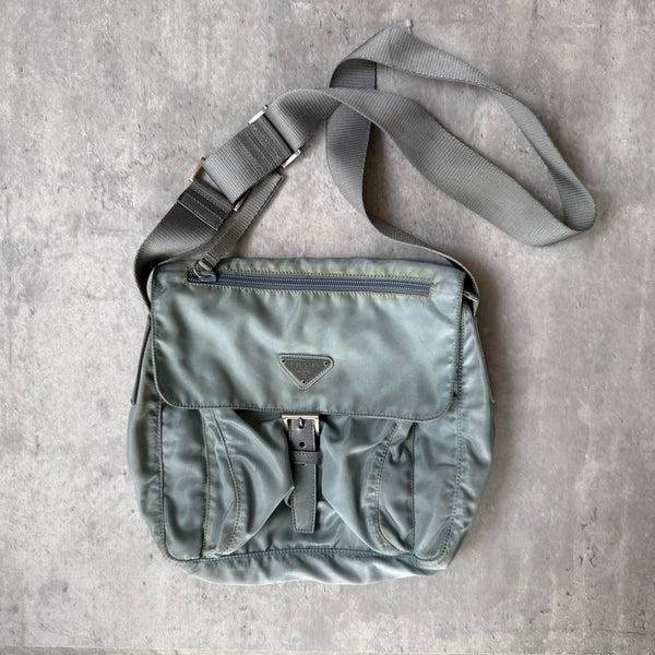 Prada Nylon Front Buckle Shoulder Bag in light blue with grey strap, zip and buckle compartments, and Prada logo plaque.