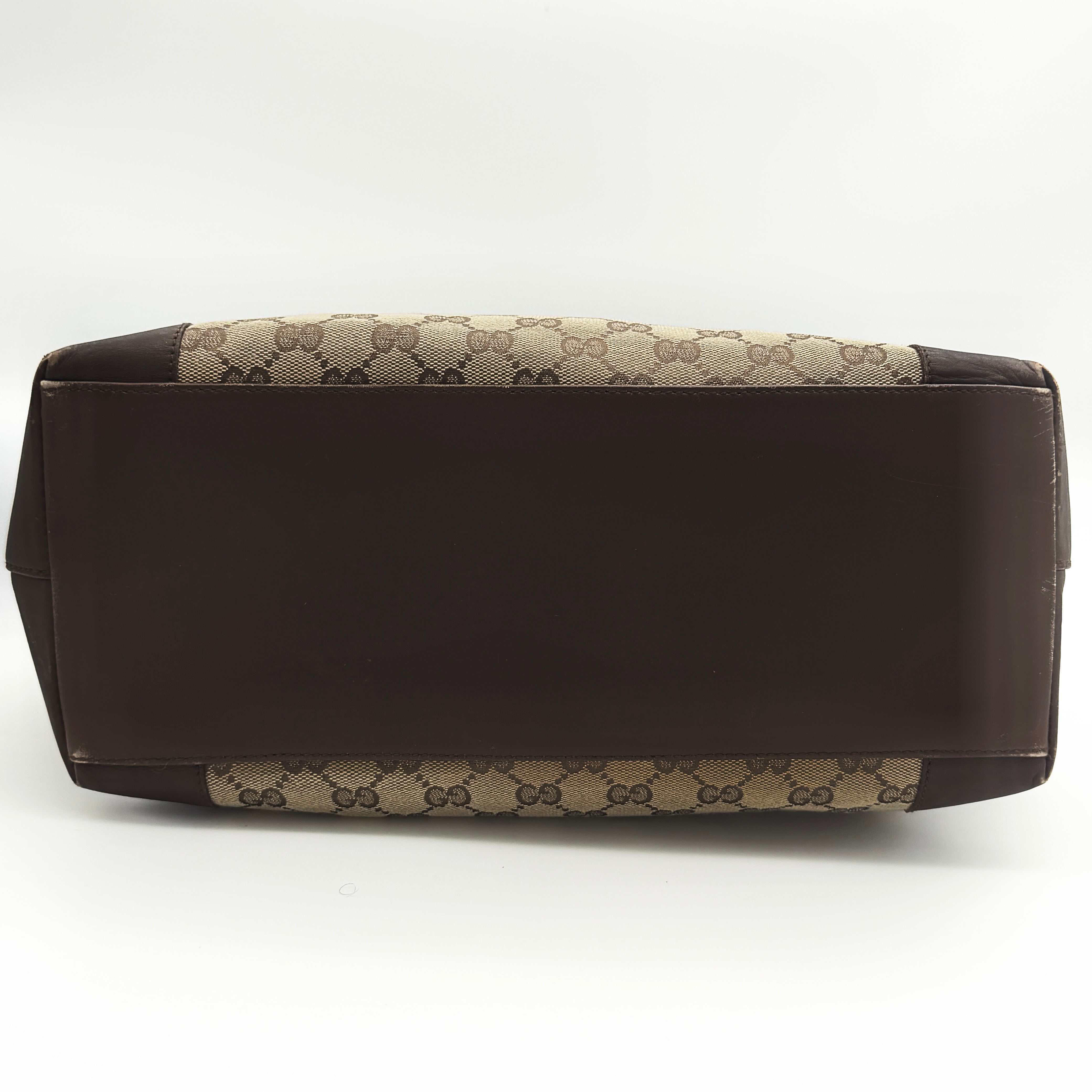 Front view of a Gucci GG Monogram Tote Bag in beige and brown canvas with dark leather trim and structured handles.