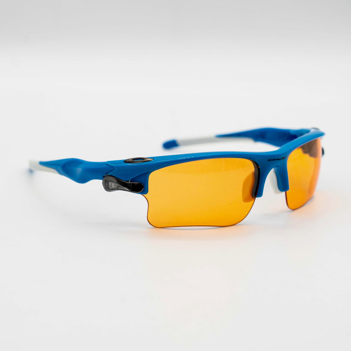 Oakley Fast Jacket OO9156-04 sunglasses in blue with orange lenses, displayed with two extra pairs of lenses, cleaning cloth and a black Oakley hard case.