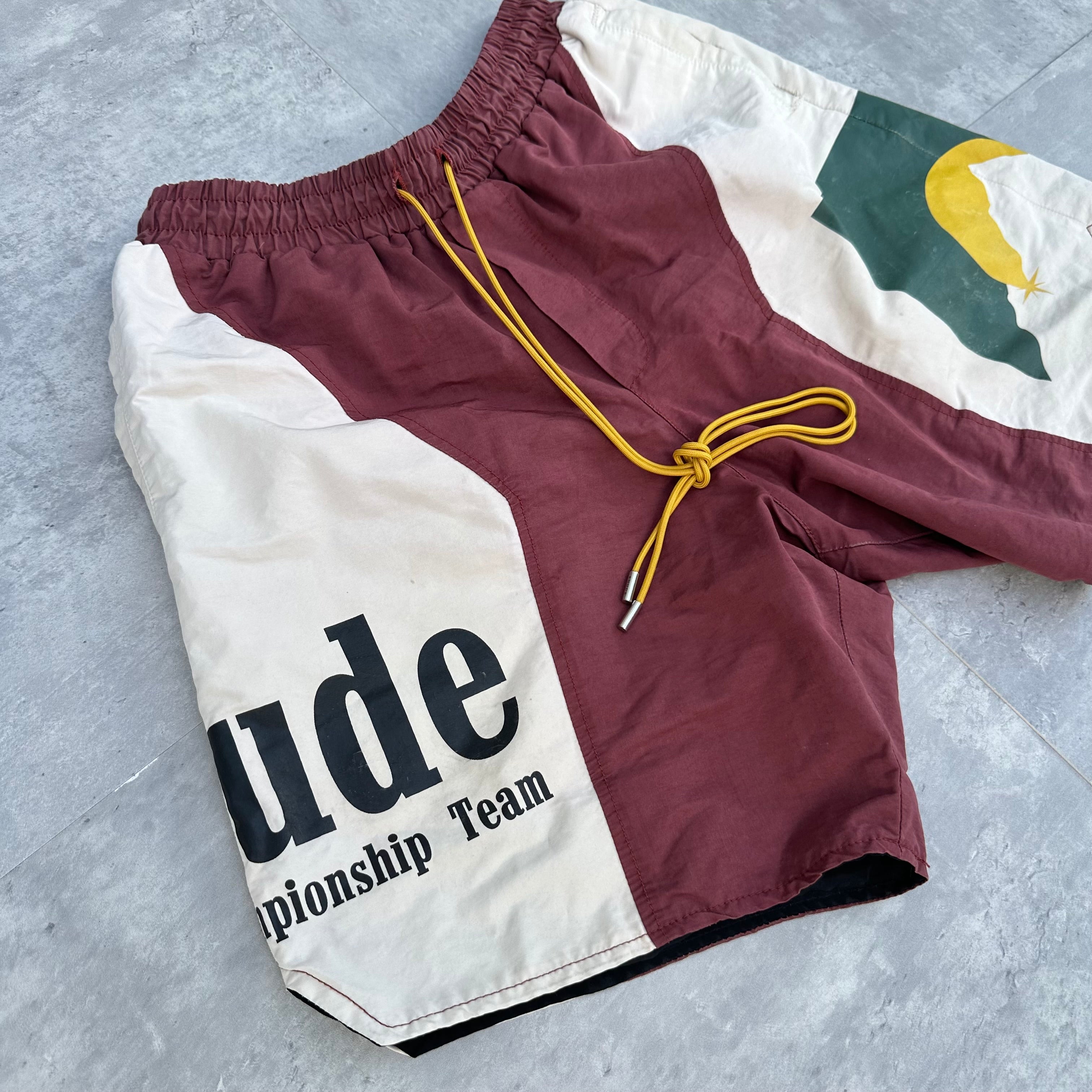 Rhude Panel Logo Shorts Maroon/White/Multi FW22, featuring championship print and moon graphic, with yellow drawstring and bold panel design.