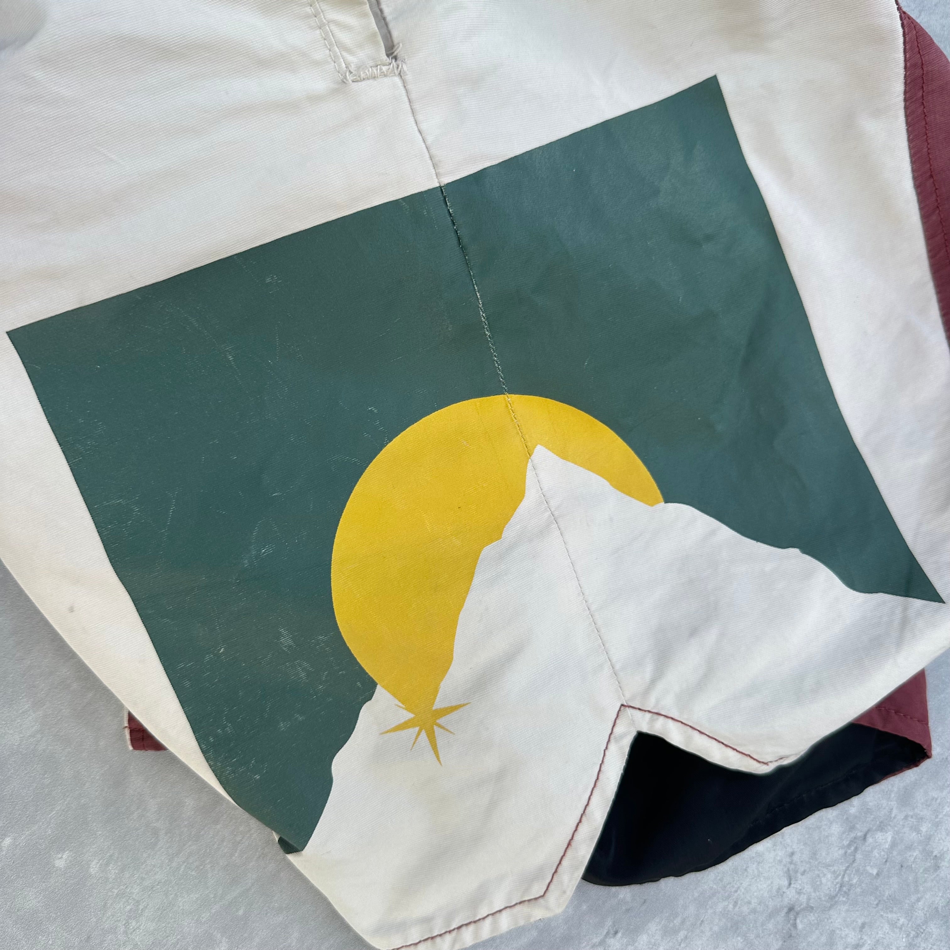 Rhude Panel Logo Shorts Maroon/White/Multi FW22, featuring championship print and moon graphic, with yellow drawstring and bold panel design.