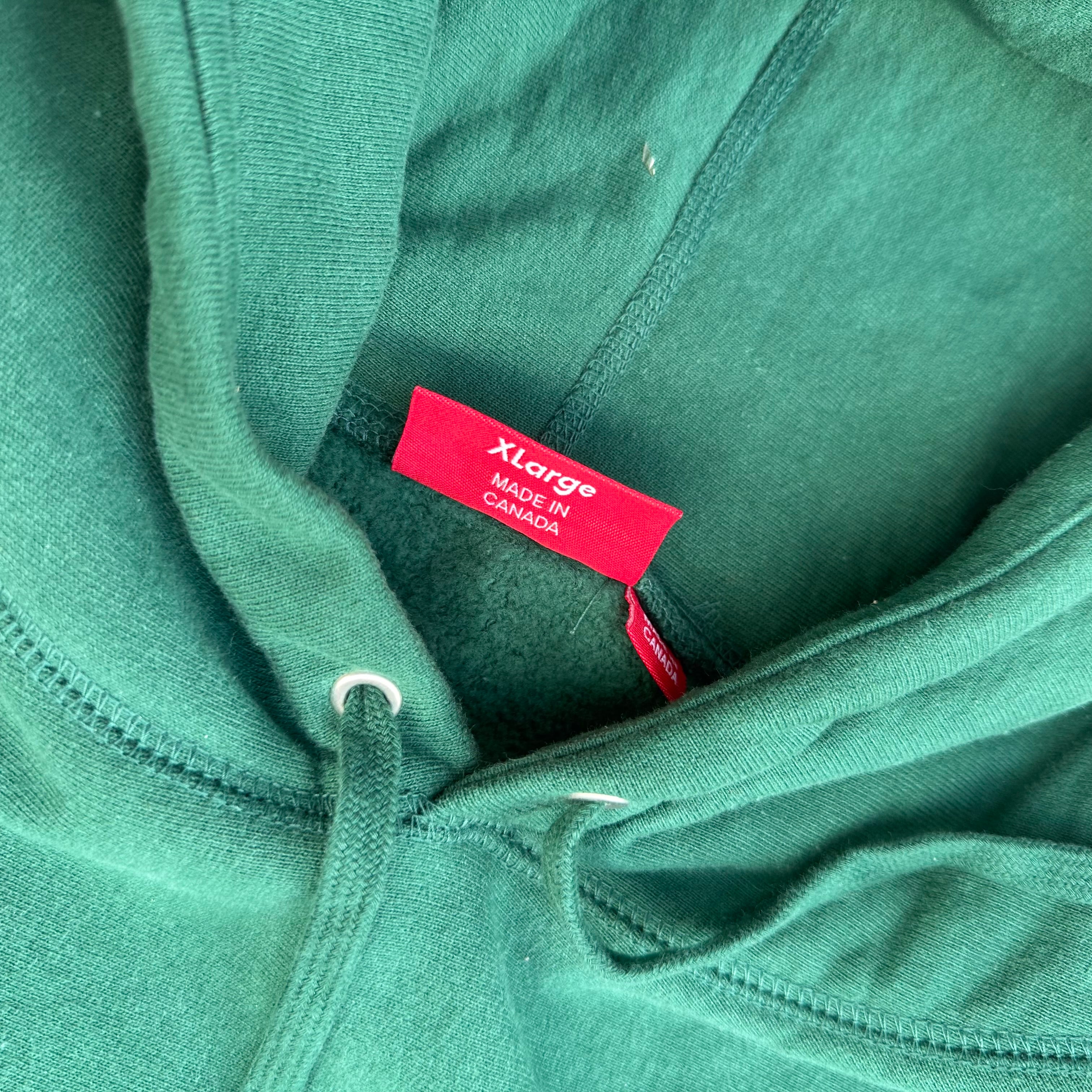 Supreme Arabic Logo Hoodie FW21 in green, featuring orange Arabic logo embroidery and kangaroo pocket, made from heavyweight cotton.